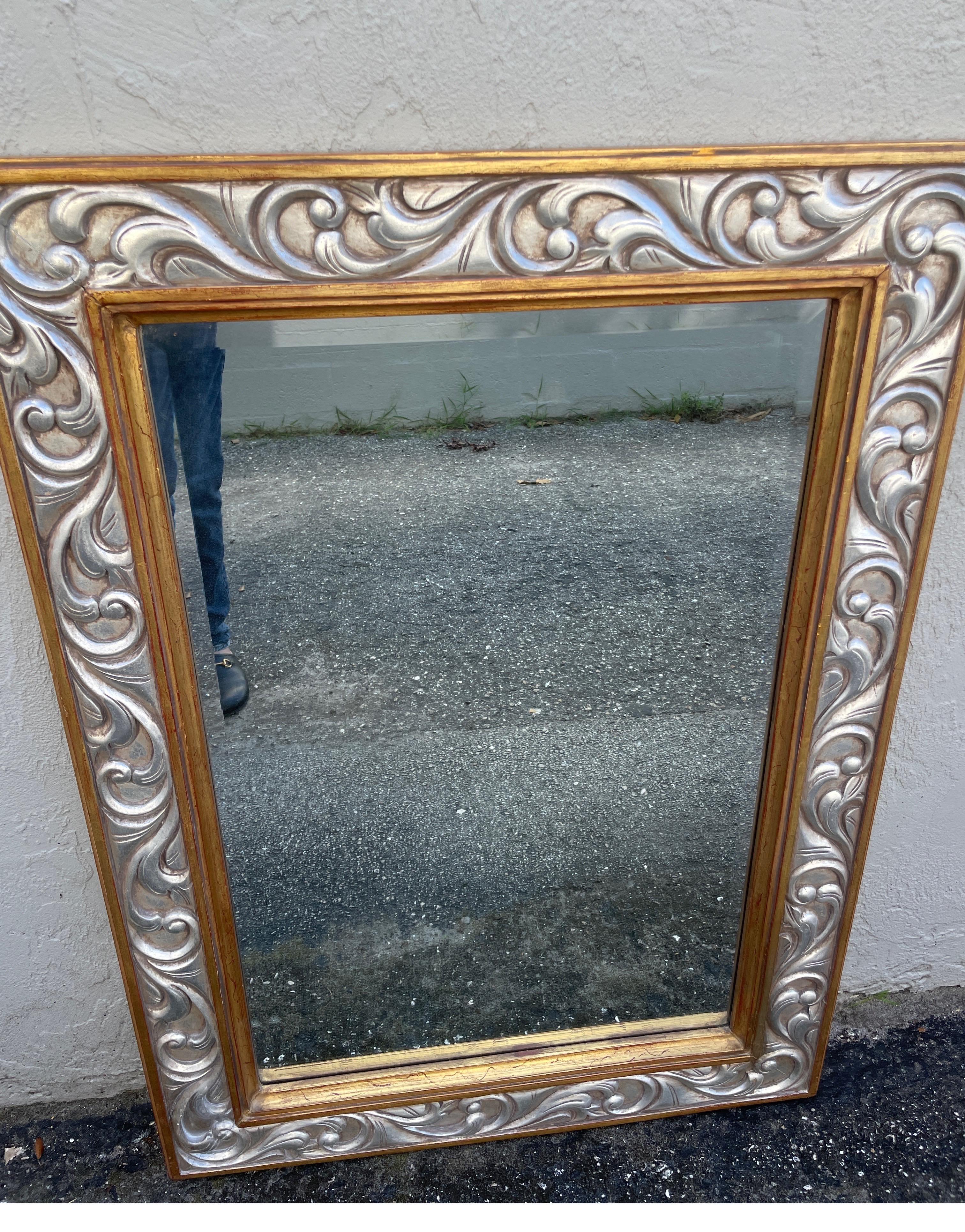 Very fine hand carved and gilded wall mirror by Harrison & Gil.  Predominantly silver gilt with gold accents.