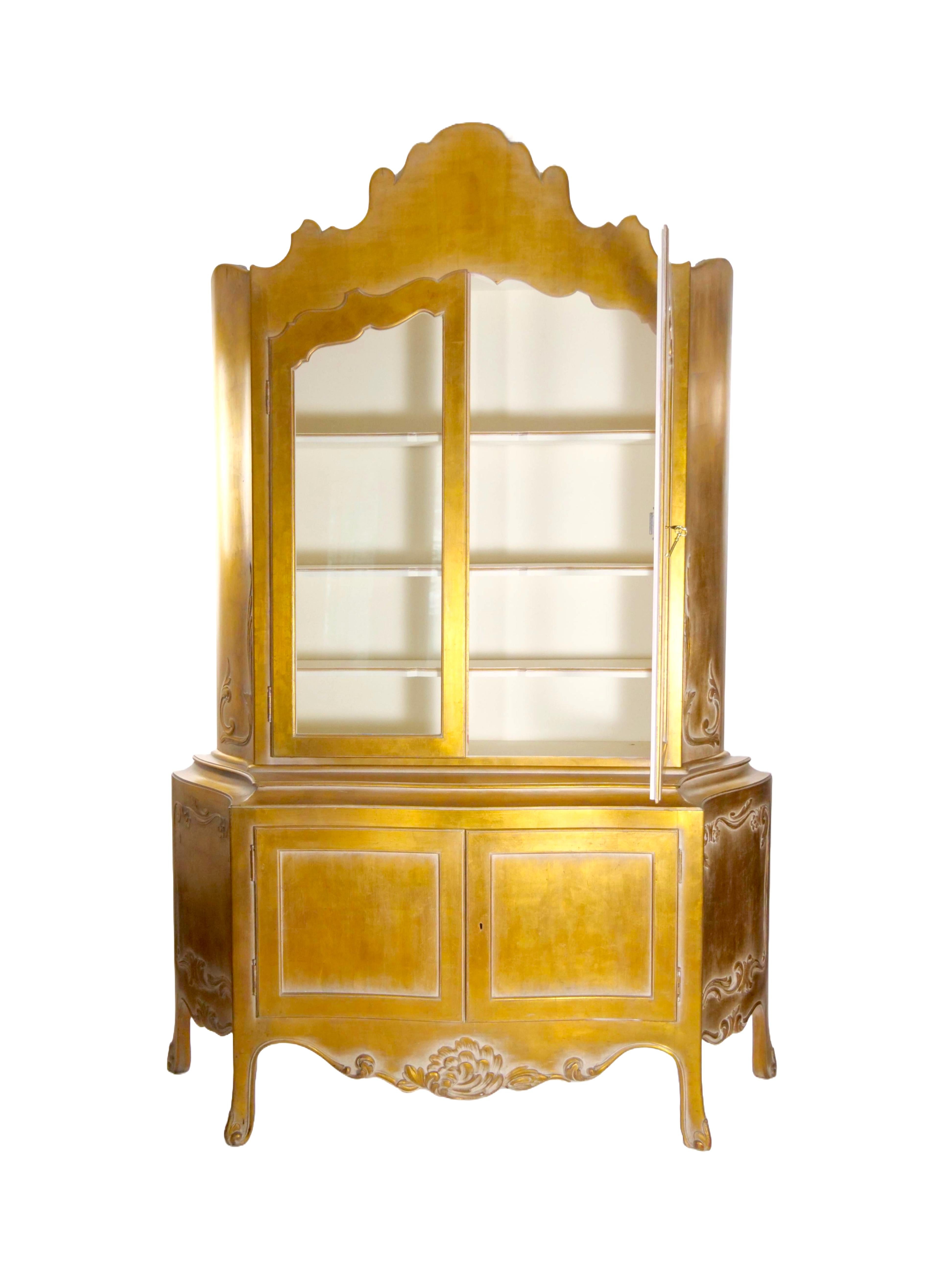 Elevate your living space with our Mid-20th Century Italian Hand-Carved Wood Gilt Gold Painted Exterior Two-Part Display Cabinet—a true testament to craftsmanship and timeless design. This exquisite cabinet showcases intricate carved wood details on