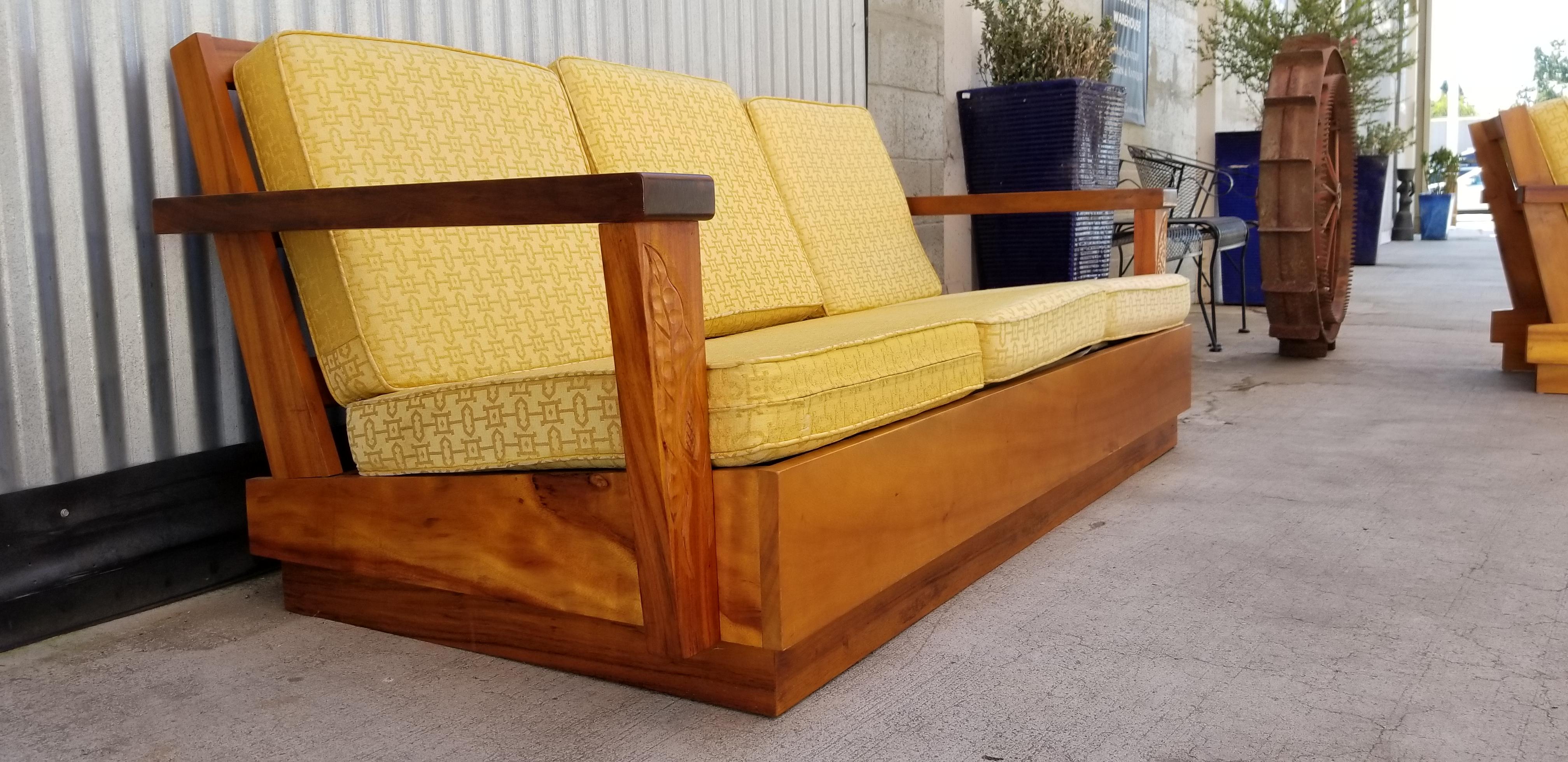 A Mid-Century Modern three-seat sofa made of the exotic, beautiful and scarce Koa from Hawaii, circa 1960s. Original finish with warm patina and depth to finish. hand-carved detail of anthuriam. Cushions in need of new upholstery, therefore, you may