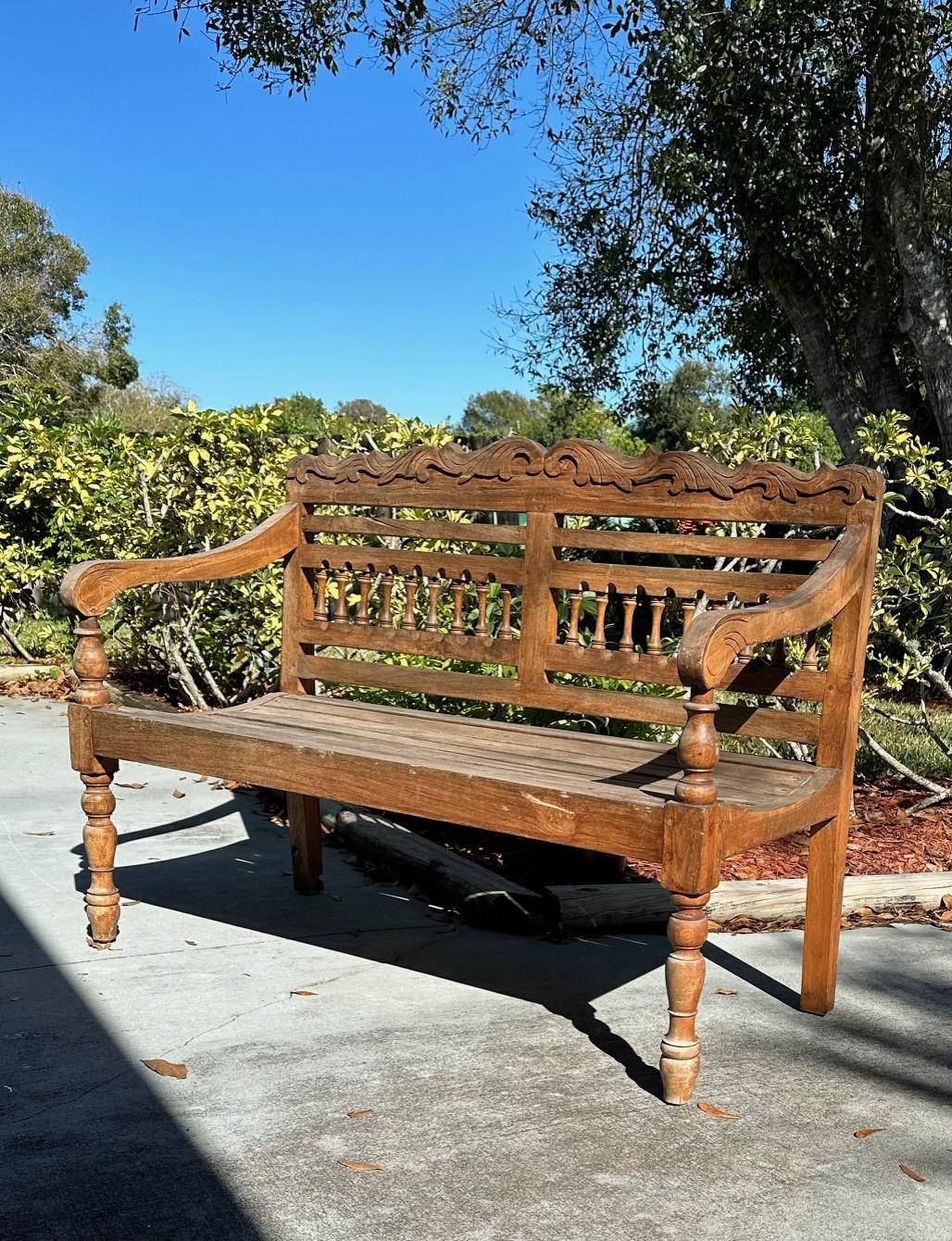 Hand Carved Indonesian 1980s Colonial Teak Wooden Garden Bench

Solid wood bench is handcrafted by skilled craftsmen with experience in working with teak wood. The seat is slatted and the back is carved. The vintage bench stands on turned front legs