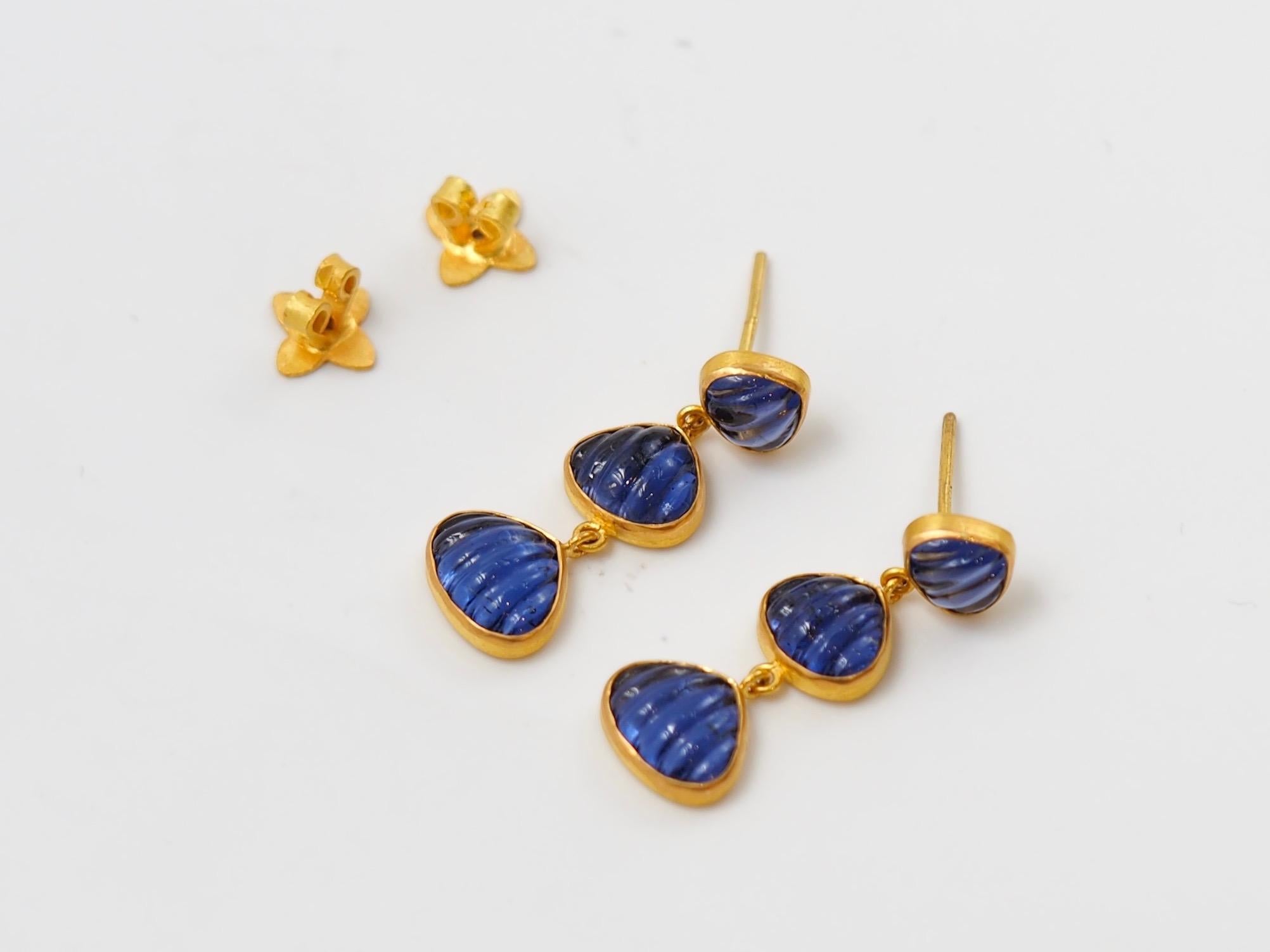 These earrings are composed of 6 iolites for a total weight of 5.8 carats. The iolites are hand-carved in the form of shells in 3 different sizes.
The shells are all set in 22 karat gold. The earrings are with a gold push / stud.
The earrings shows