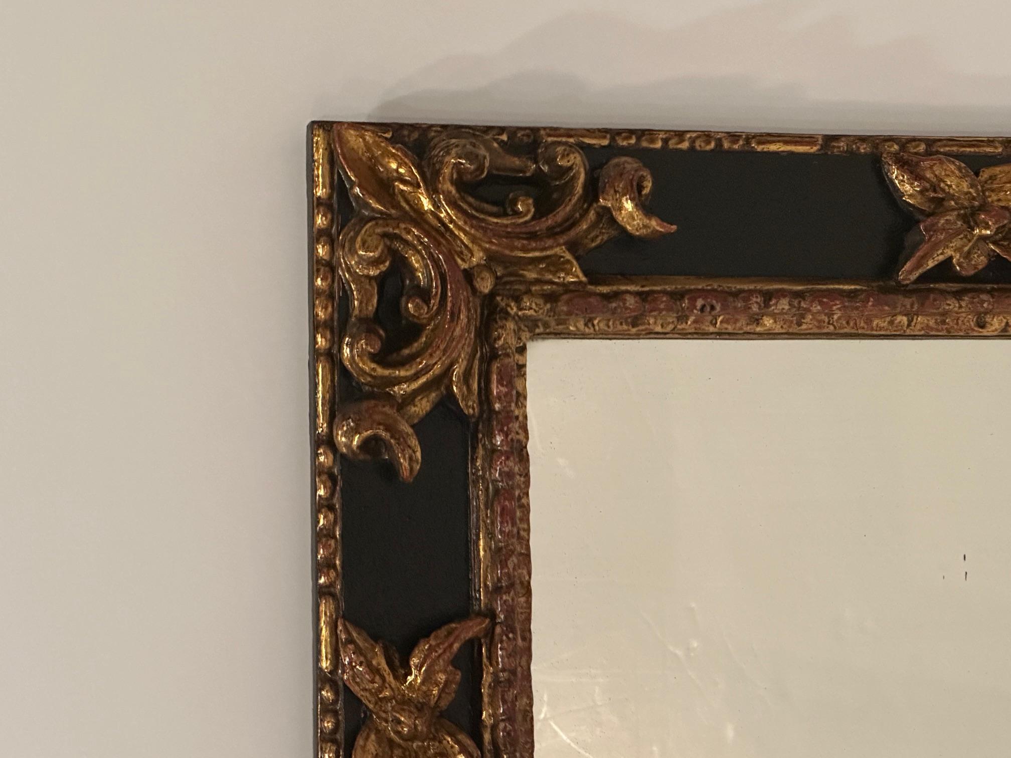 Miroir dramatique ébonisé et doré, de grande taille et fortement sculpté, avec un motif stylisé de fleur de lys.  Miroir  17 l 24 h
