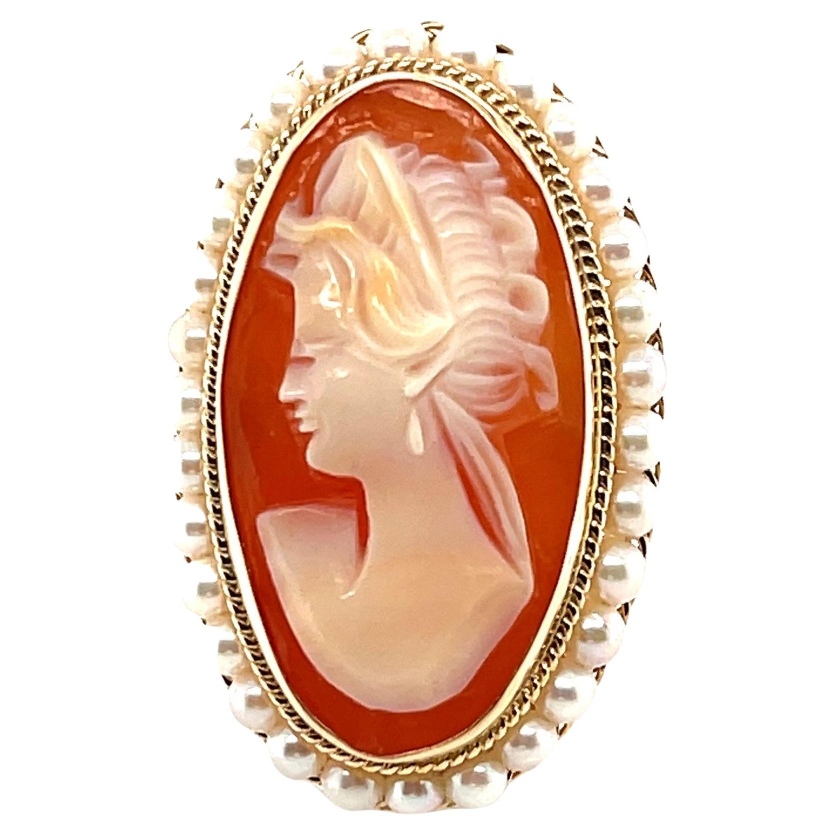 This lovely cocktail ring features a large, elongated shell cameo that was beautifully hand carved in Italy. The cameo is bezel set and encircled with 3mm seed pearls that have been hand-strung on fine gold wire. The pearls sit atop an intricate