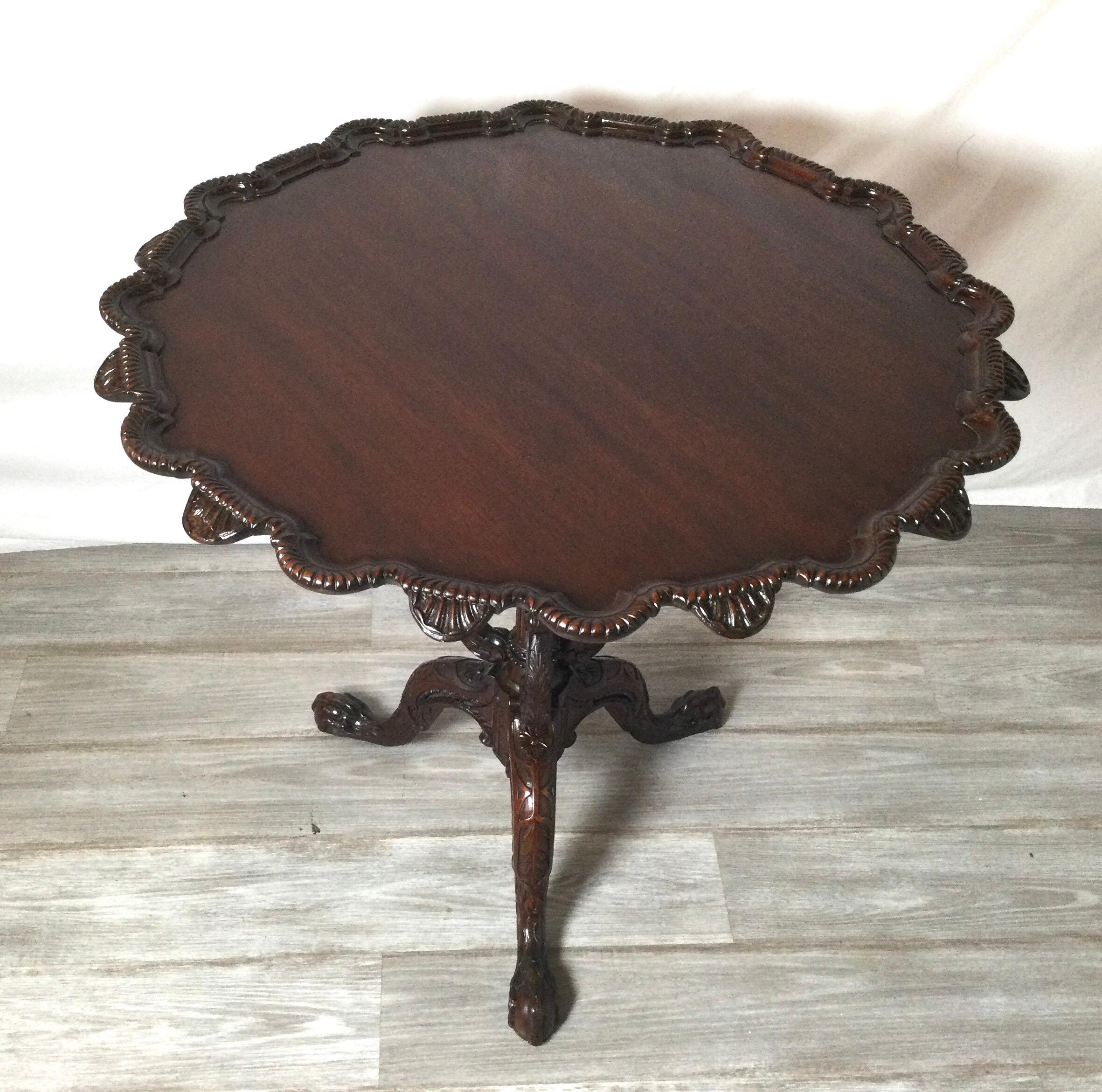 Beautifully hand carved Mahogany style Irish Chippendale tilt top tea table. The carved top border with with intricately carved tri-pod base. The top with a recent French Polish.
