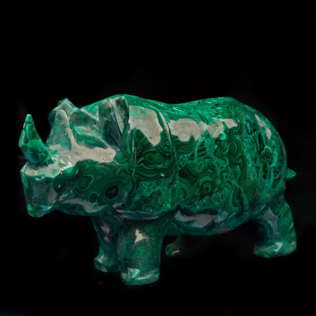 Diese üppige grüne Kupferkarbonat-Mineralprobe wurde fachmännisch von Hand in ein 7,5 Pfund schweres Rhinozeros geschnitzt und von Hand zu einem brillanten Glanz poliert, um seine prächtigen Farben und Bänder hervorzuheben. Malachit wurde in der