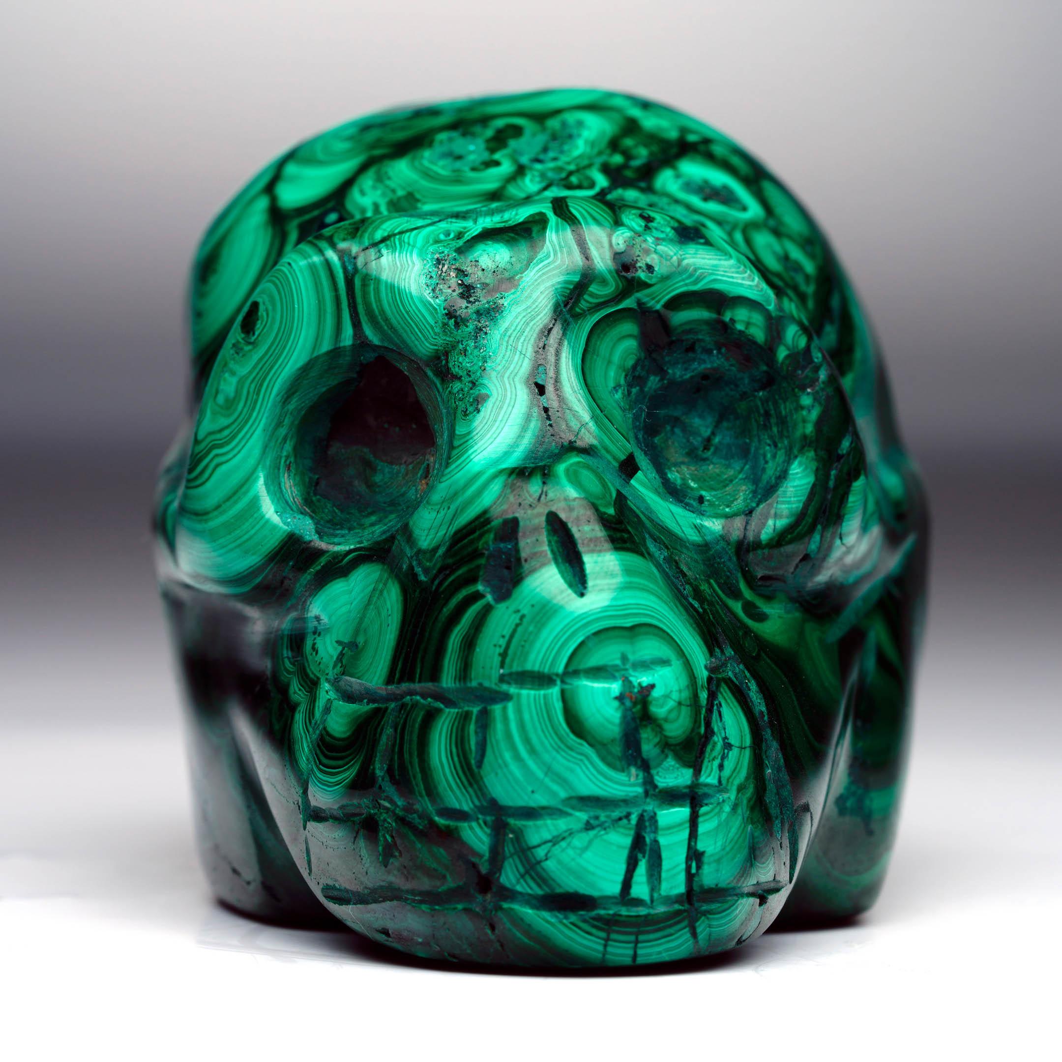 Questo sorprendente teschio di malachite è stato meticolosamente intagliato a mano per mostrare la bellezza naturale della pietra e offrire un'audace dichiarazione decorativa. Bande vivaci di smeraldo intenso e verde più chiaro scorrono sulla