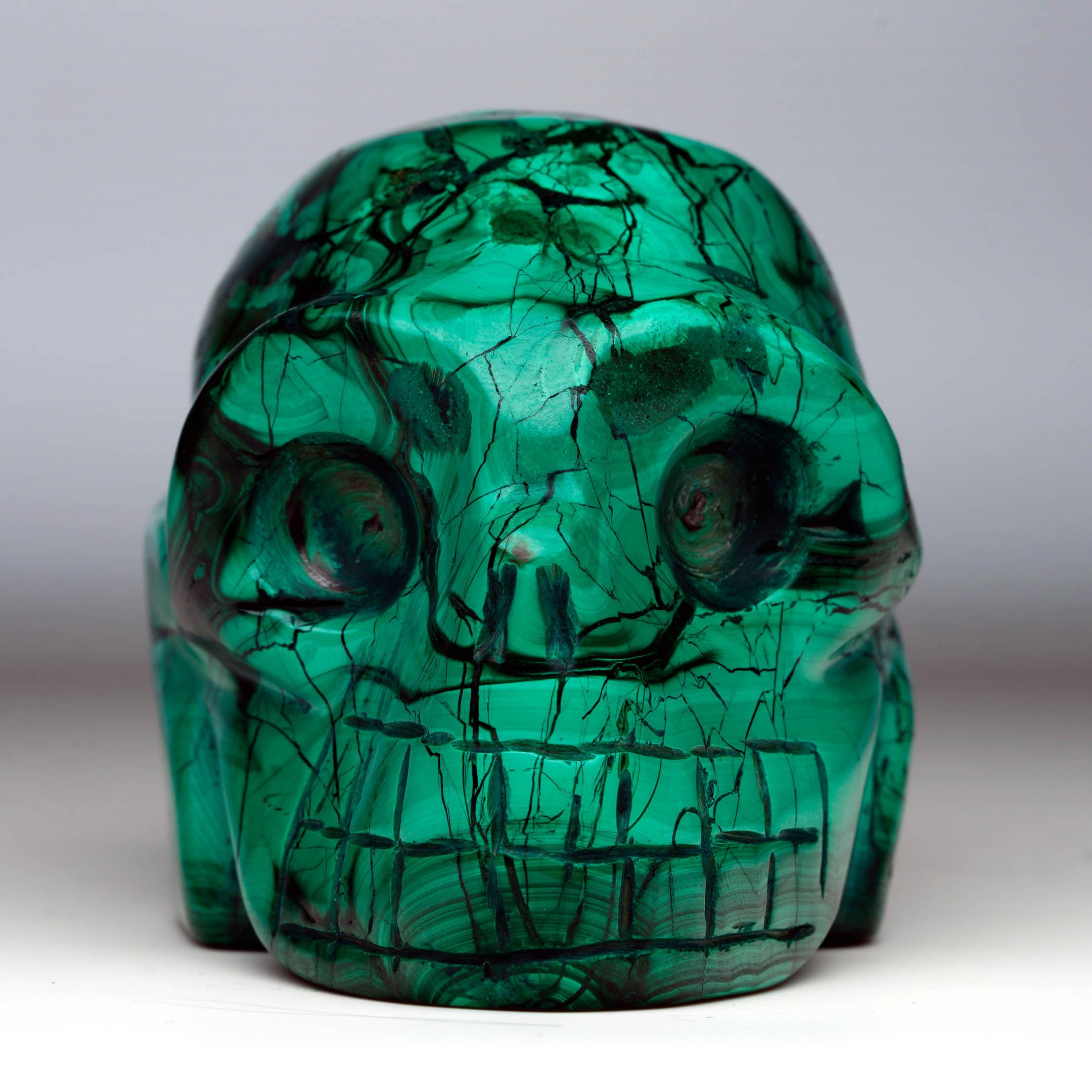 Esta calavera de malaquita tallada a mano captura la belleza característica del mineral en una refinada forma decorativa. Llamativas bandas de color esmeralda intenso y verde más claro crean espectaculares anillos concéntricos, remolinos fluidos y
