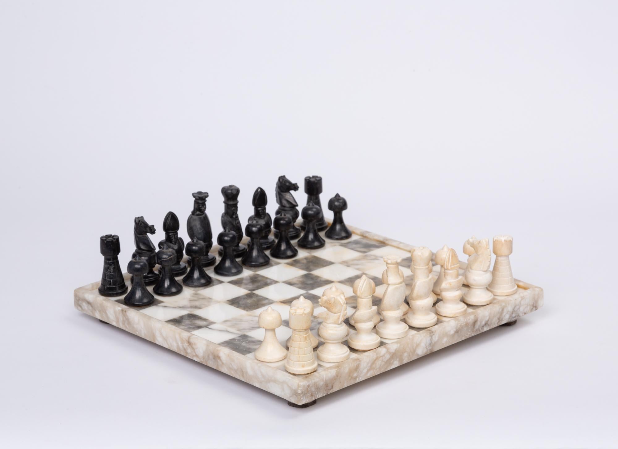 Hand carved marble and bone chess set. This stunning monochrome set features a marble checkerboard inset into a thicker marble frame, which sits atop short marble feet. The intricate chess pieces are hand carved marble and bone, and compliment the