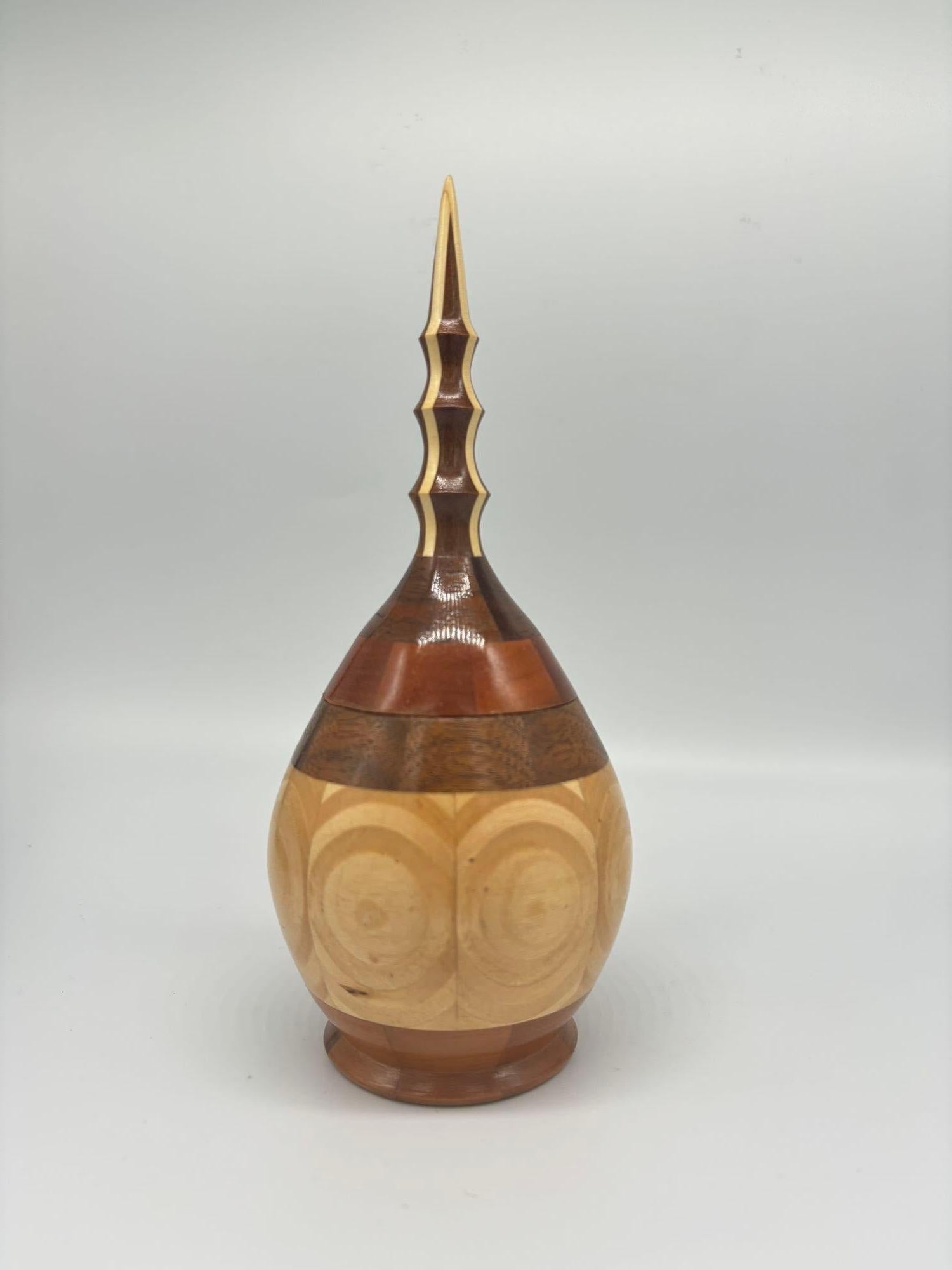 Presenting a stunning Hand Carved Marquetry Inlay Pear Shaped Vessel with Lid. Crafted with precision and care, this exquisite vessel showcases intricate marquetry inlay, adding a touch of artistry and elegance to any space. Its unique pear shape