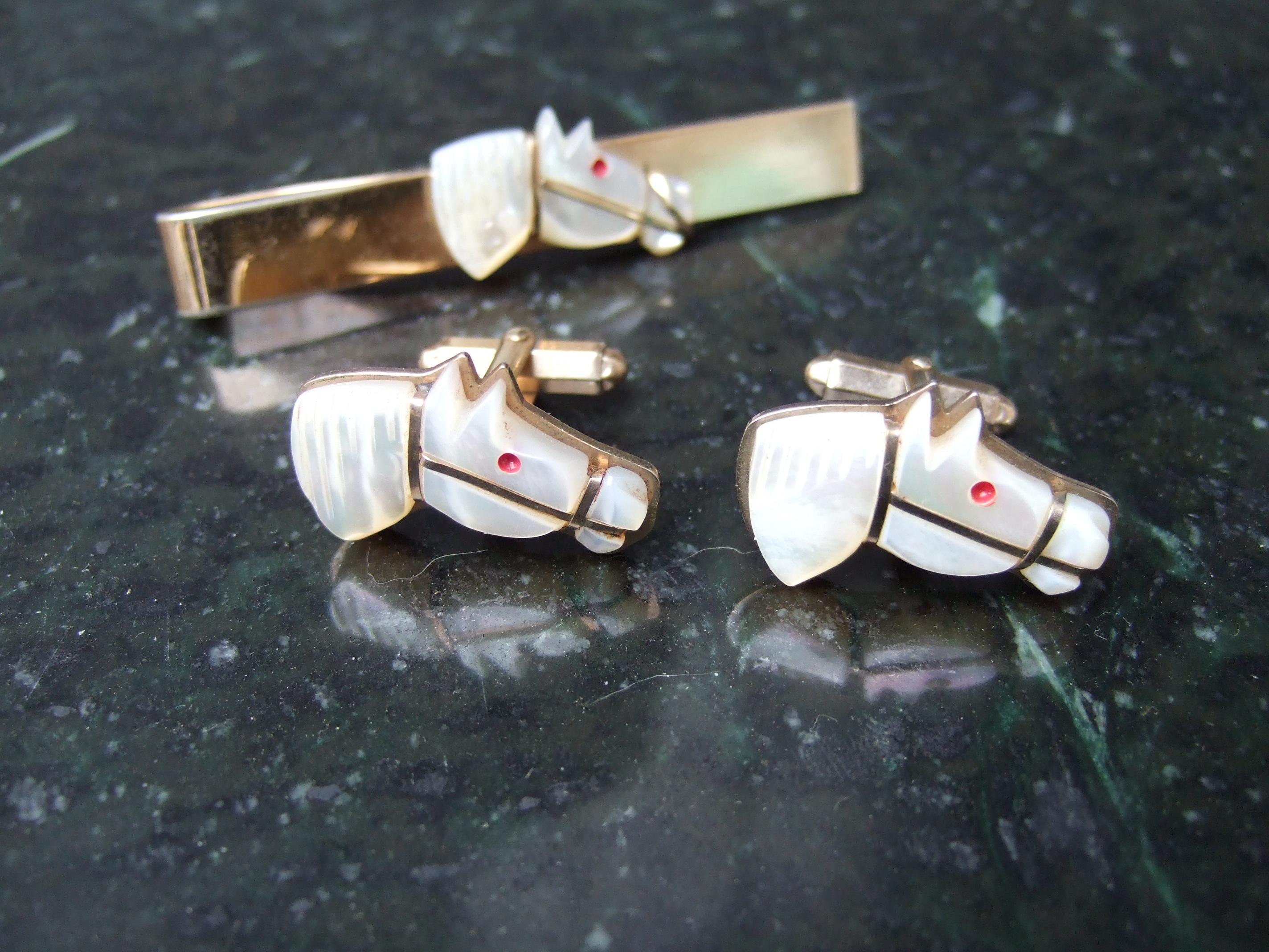 Hand carved mother of pearl equine cufflinks & tie bar set c 1950s
The unique set is designed with a trio of horse figures designed 
from mother of pearl shell

Designed with gilt metal bridals & red enamel eyes
Makes a very elegant accessory