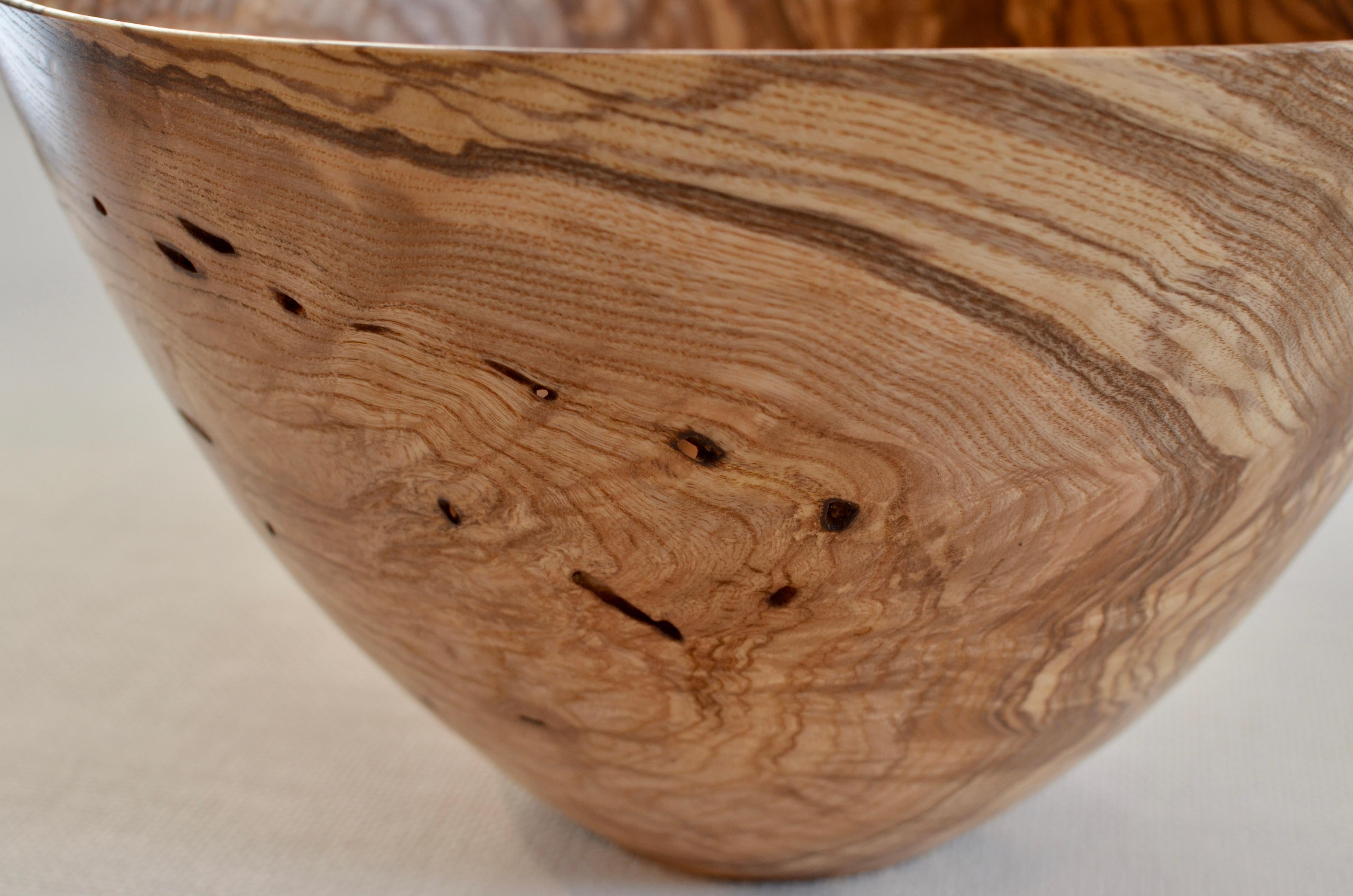 Hand-carved, oiled 100-year-old Ash wood bowl with natural grain & holes. Created using wood only from fallen Ash trees. One of a kind.
     