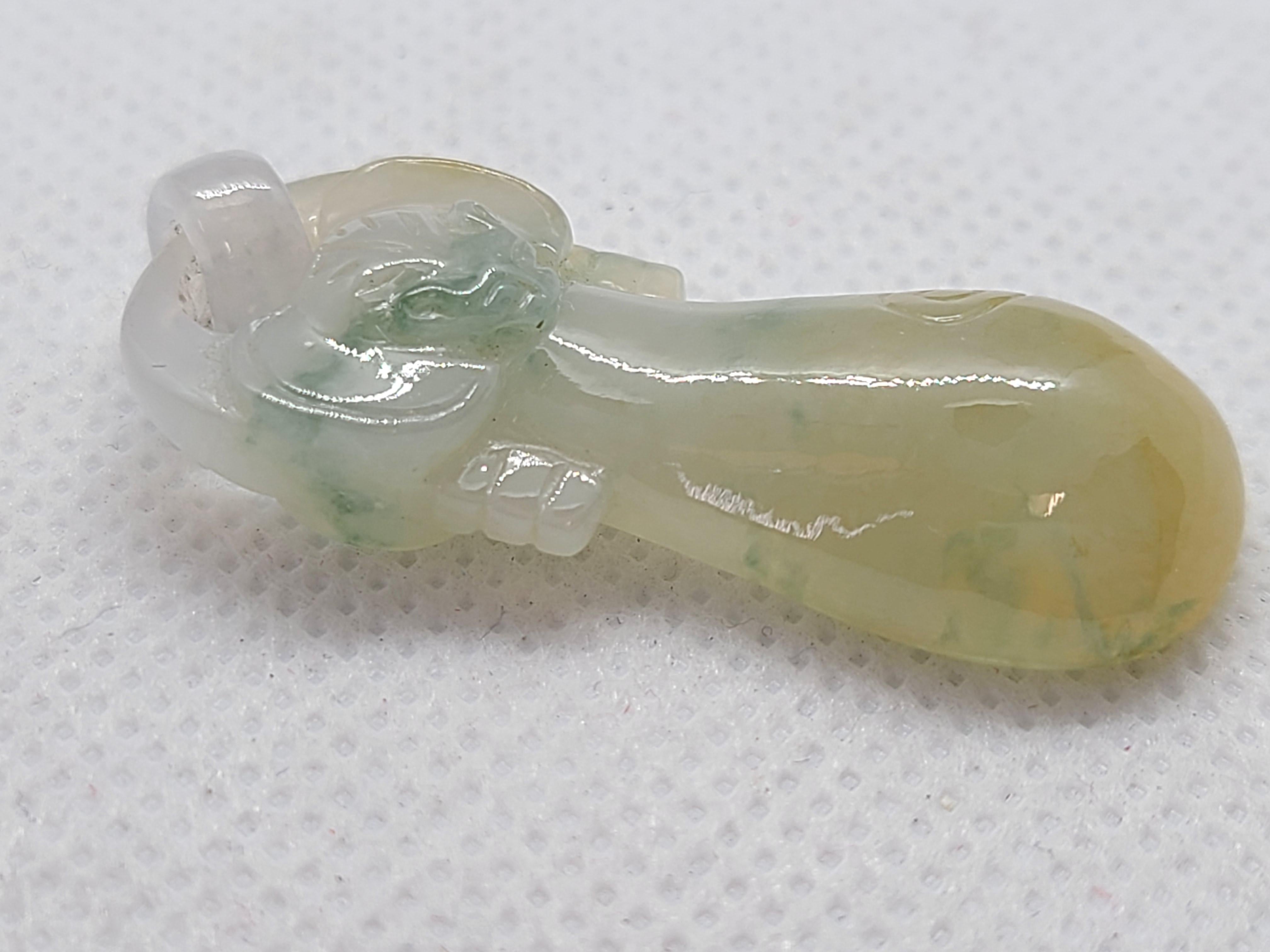 Questo ciondolo in giada naturale tricolore, caratterizzato da armoniose tonalità di marrone, grigio e verde, è finemente intagliato nella forma di una pipa tradizionale, l'iconico strumento musicale cinese, abbinato a un motivo Ruyi che simboleggia