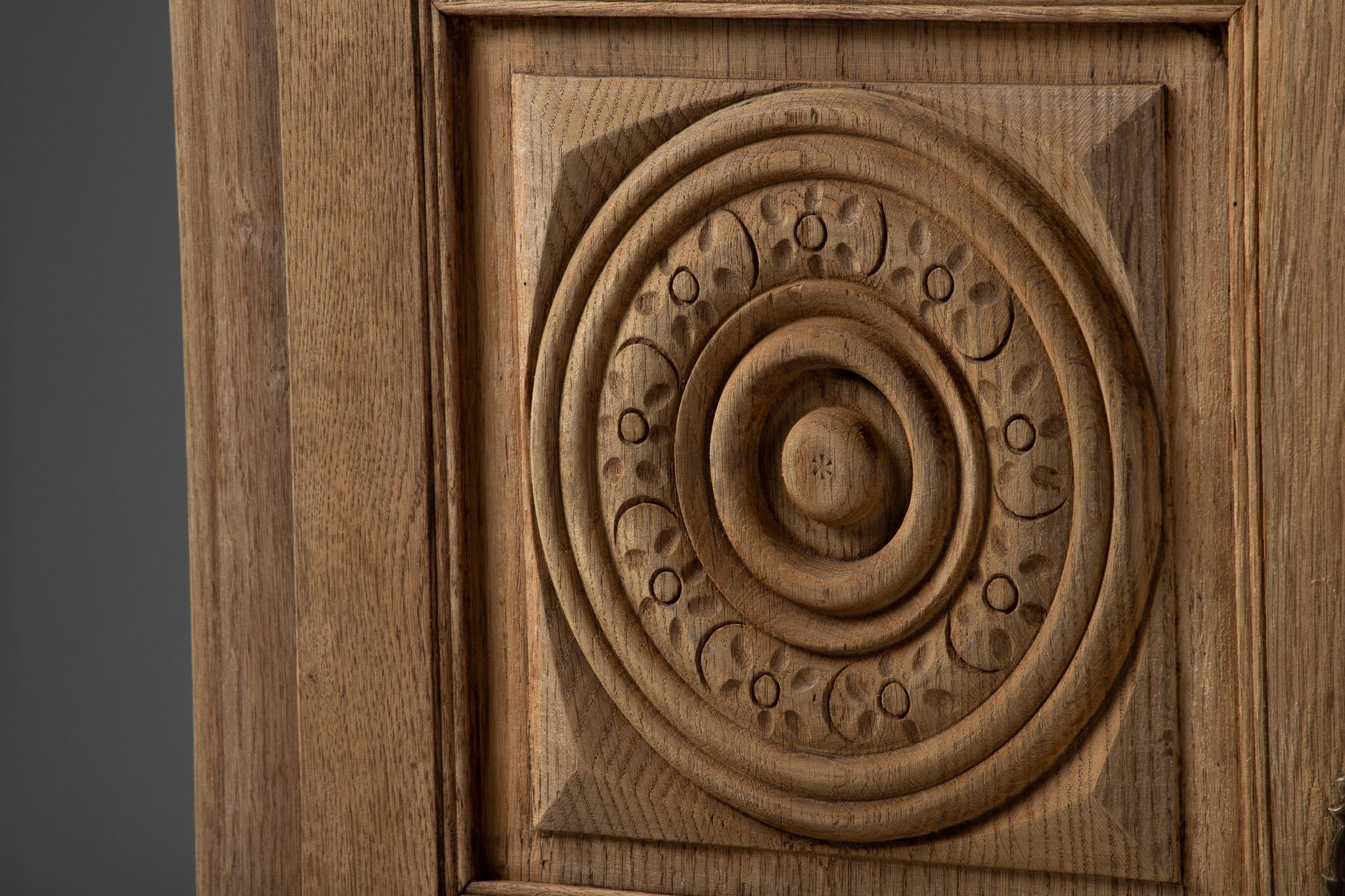 Armoire in Carved Oak with Rosette Panels, France, 1950s

A stately presence marked by repetition and relief, this French armoire composes its façade in a series of rhythmic medallions—twelve in total—each a concentric carving of rings, dots, and