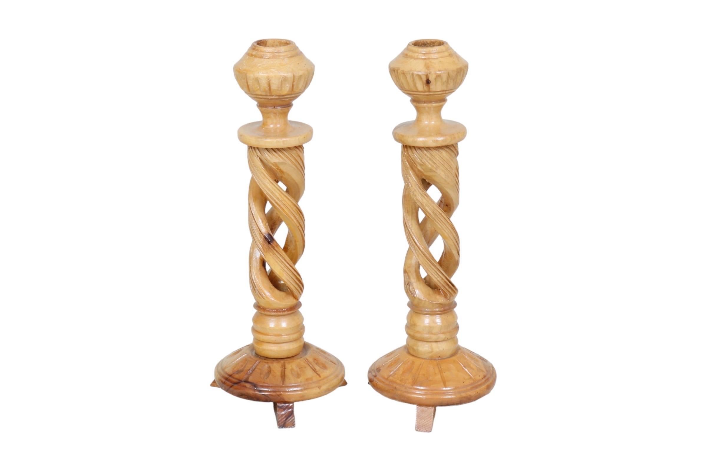 A pair of hand carved spiral candlestick holders made of olive wood. Acorn shaped sconces top pierced columns carved with three reeded spirals. Sconces and round bases are carved with a simple egg and dart like pattern, raised on three block feet.