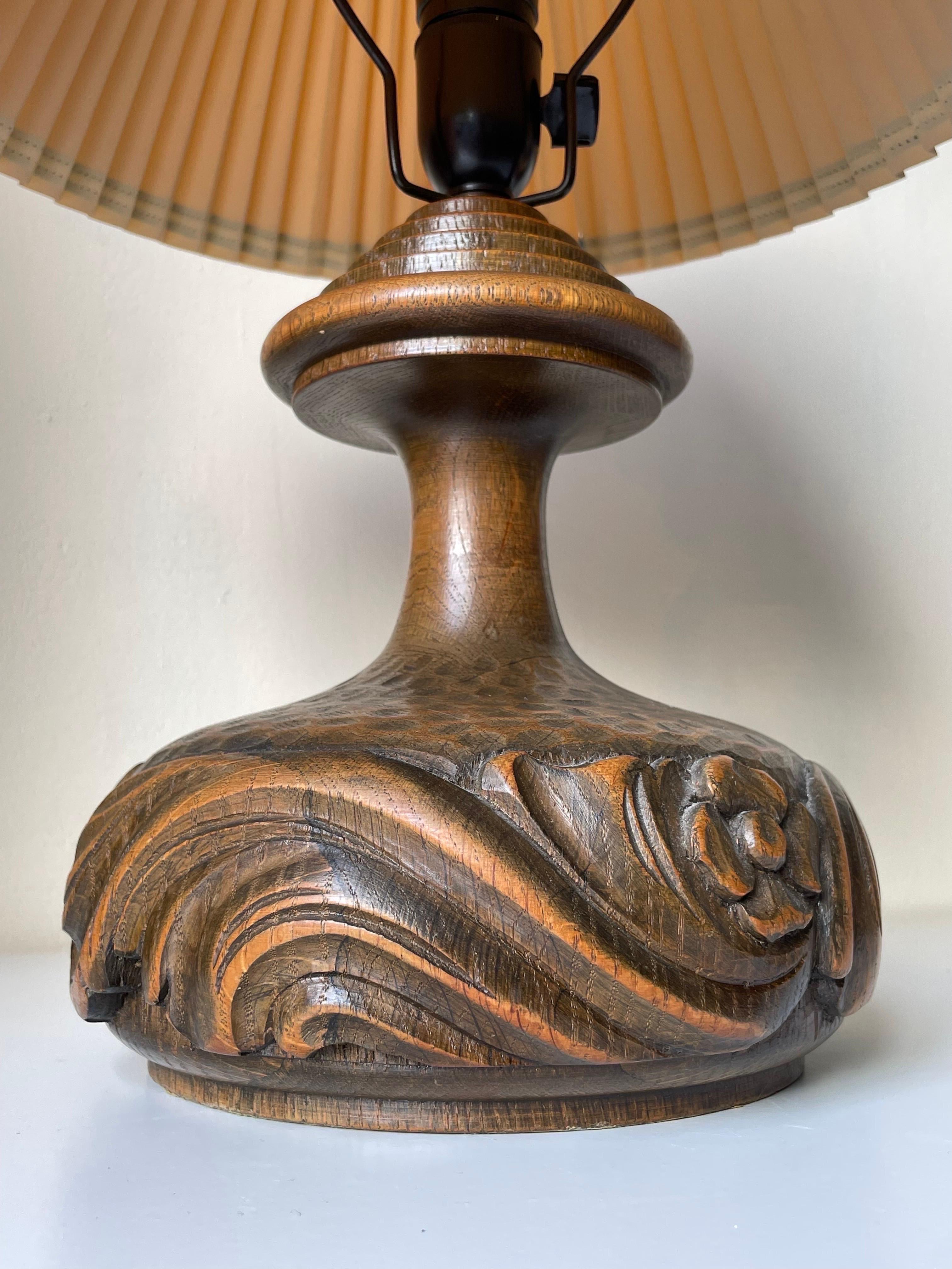 1940s lacquered solid wooden table lamp with swirling organic hand-carved relief decorations around the heavy body. Smooth slender neck with wide tiered architectural top. Original black fitting with switch and brass shade holder. Beautiful vintage