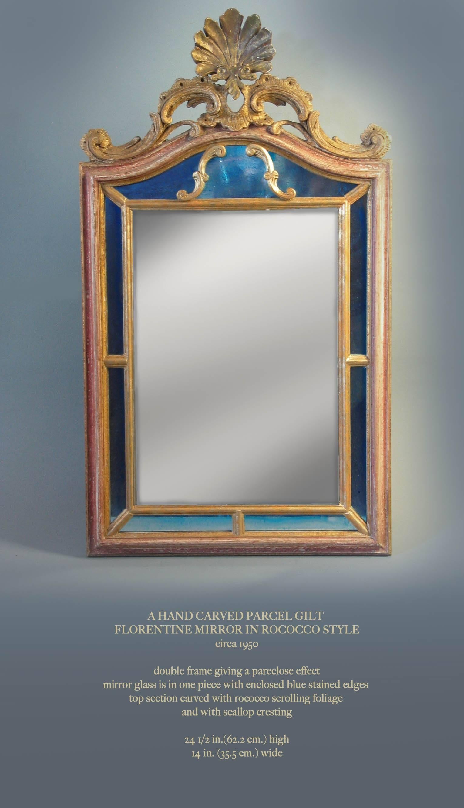 A hand-carved parcel-gilt Florentine mirror in Rococo style (Circa 1950), Double frame giving a pare close effect mirror glass is in one piece with enclosed blue stained edges, top section is carved with Rococo scrolling foliage and scallop