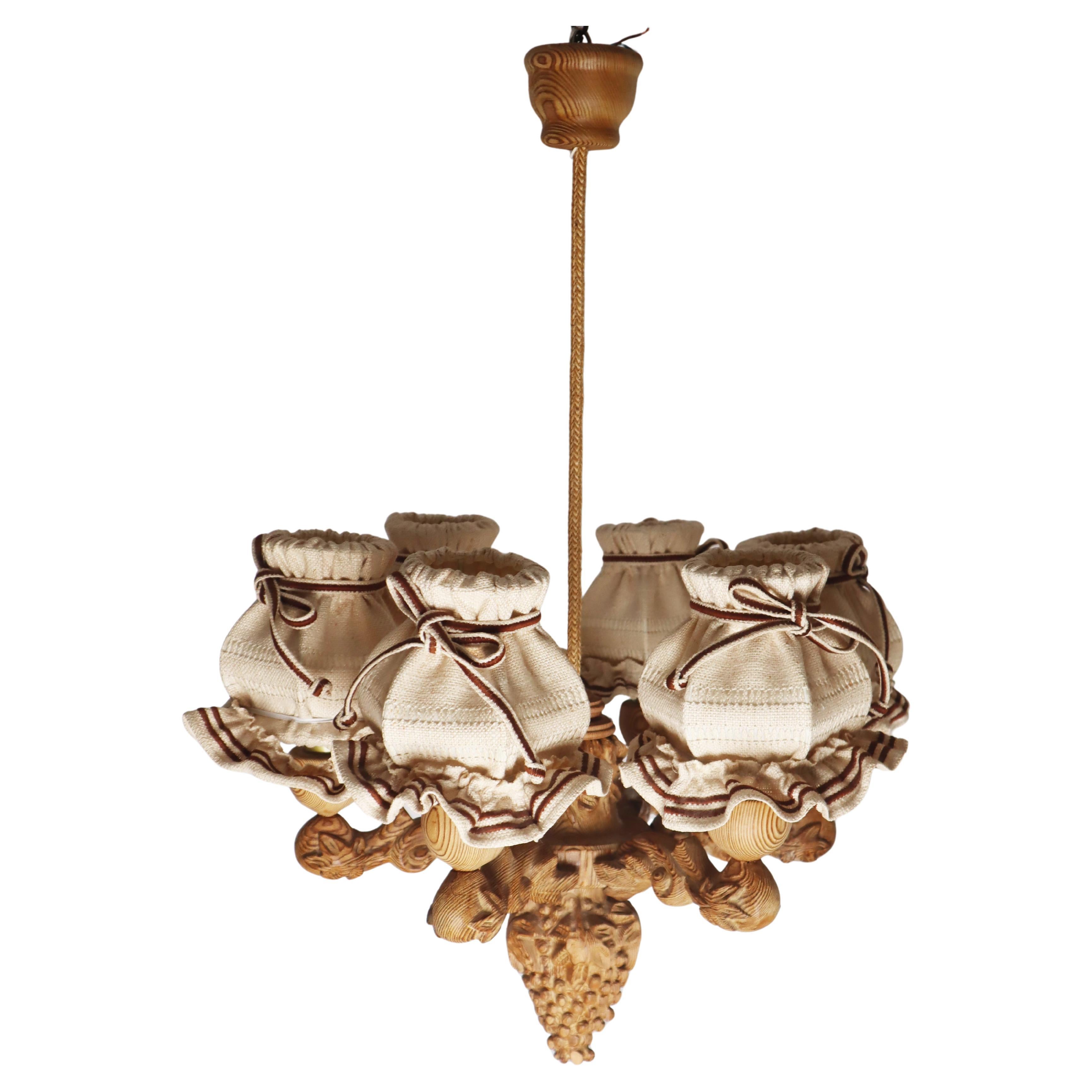 Questo elaborato lampadario intagliato in stile scandinavo è davvero unico. È stato realizzato a mano in un laboratorio d'artista in Germania. Il lampadario inizia con un grappolo d'uva alla base del lampadario. I bracci del lampadario sono