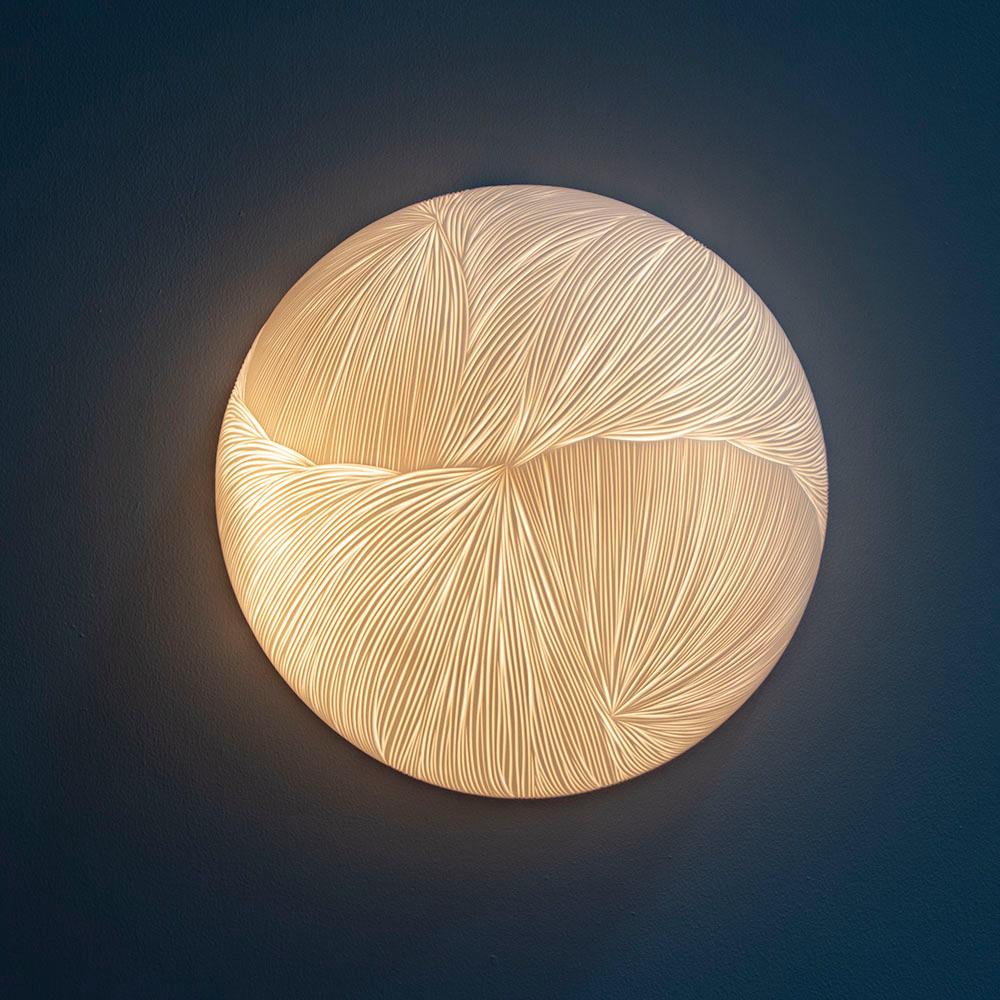 Drape takes inspiration from drapery and the use of chiaro- scuro. Drape is a hand-carved porcelain semisphere. Each lamp is designed and carved just as if it was a piece of fabric, overlapping another. The chiaro scuro effect is made even more