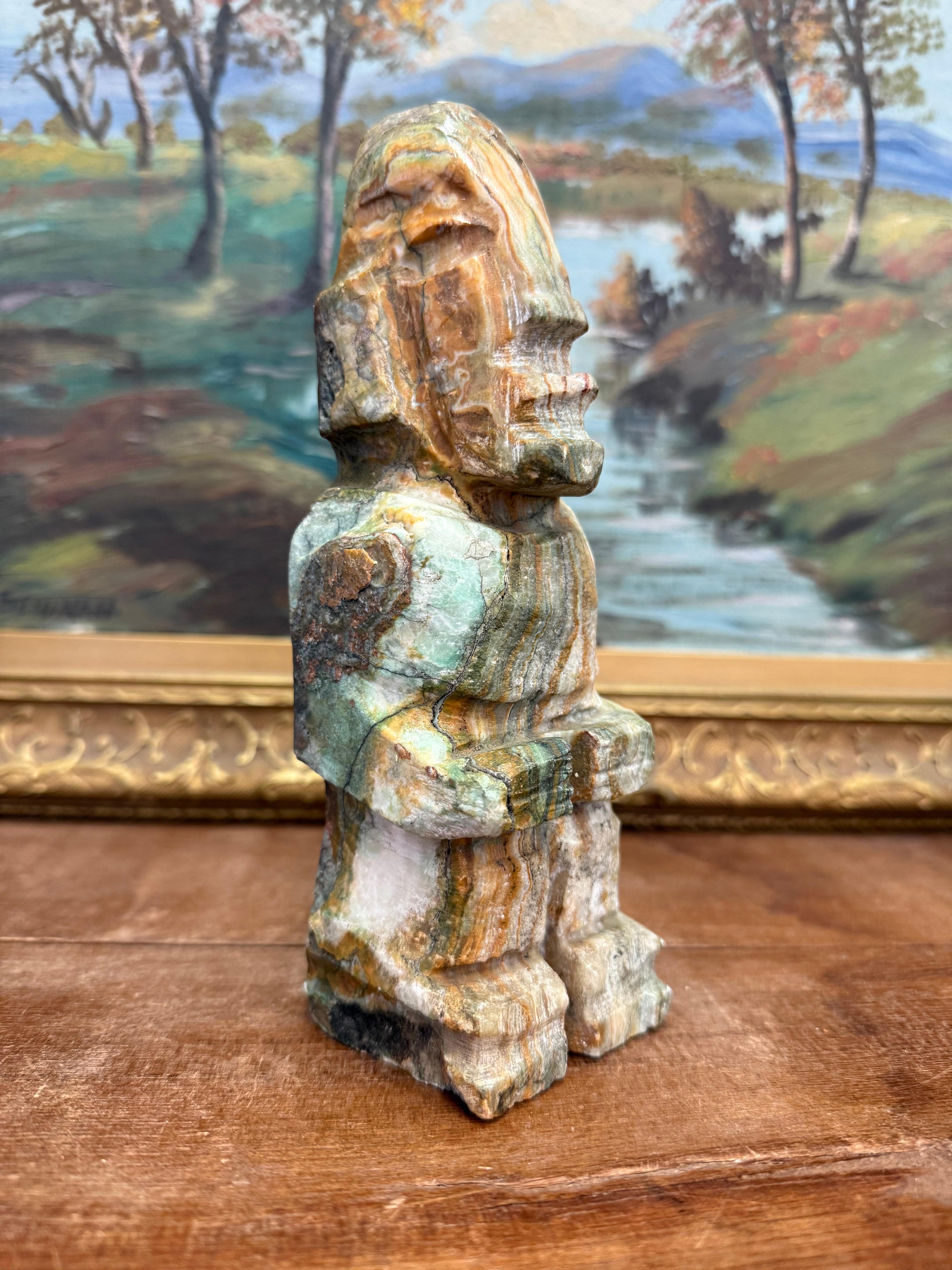 Questa statua in onice scolpita a mano di colore giada presenta uno stile artistico precolombiano, tribale e indigeno, che forse ricorda le antiche sculture mesoamericane o andine. La forma geometrica a blocchi della figura e i tratti espressivi del