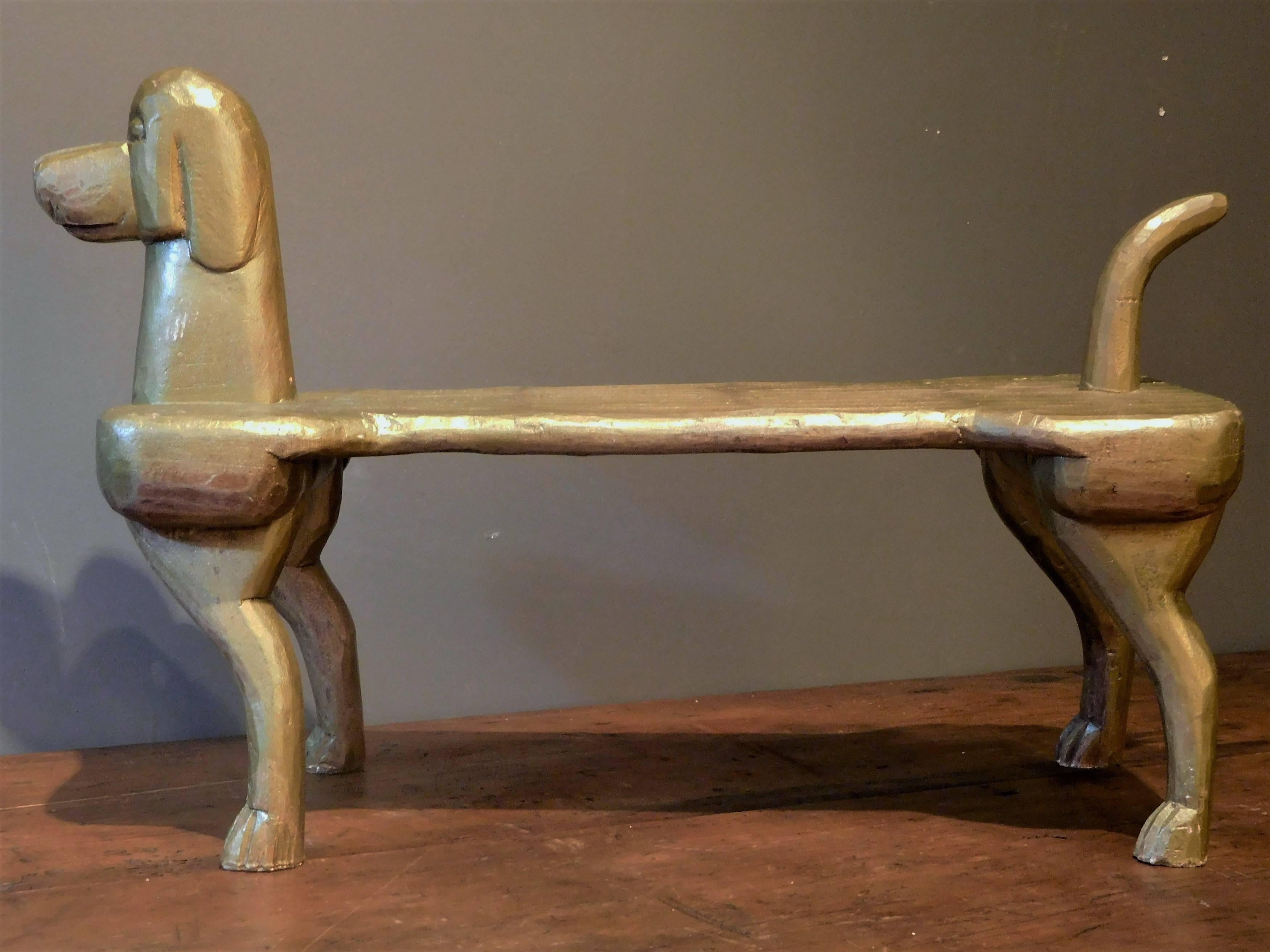 This hand-carved, gold-painted wooden footstool, a sculpture of a glorified dog, is attributed to the workshop of artist Stephen Huneck at Dog Mountain in St. Johnsbury, Vermont. It exemplifies Huneck's love of dogs and his humorous and tolerant