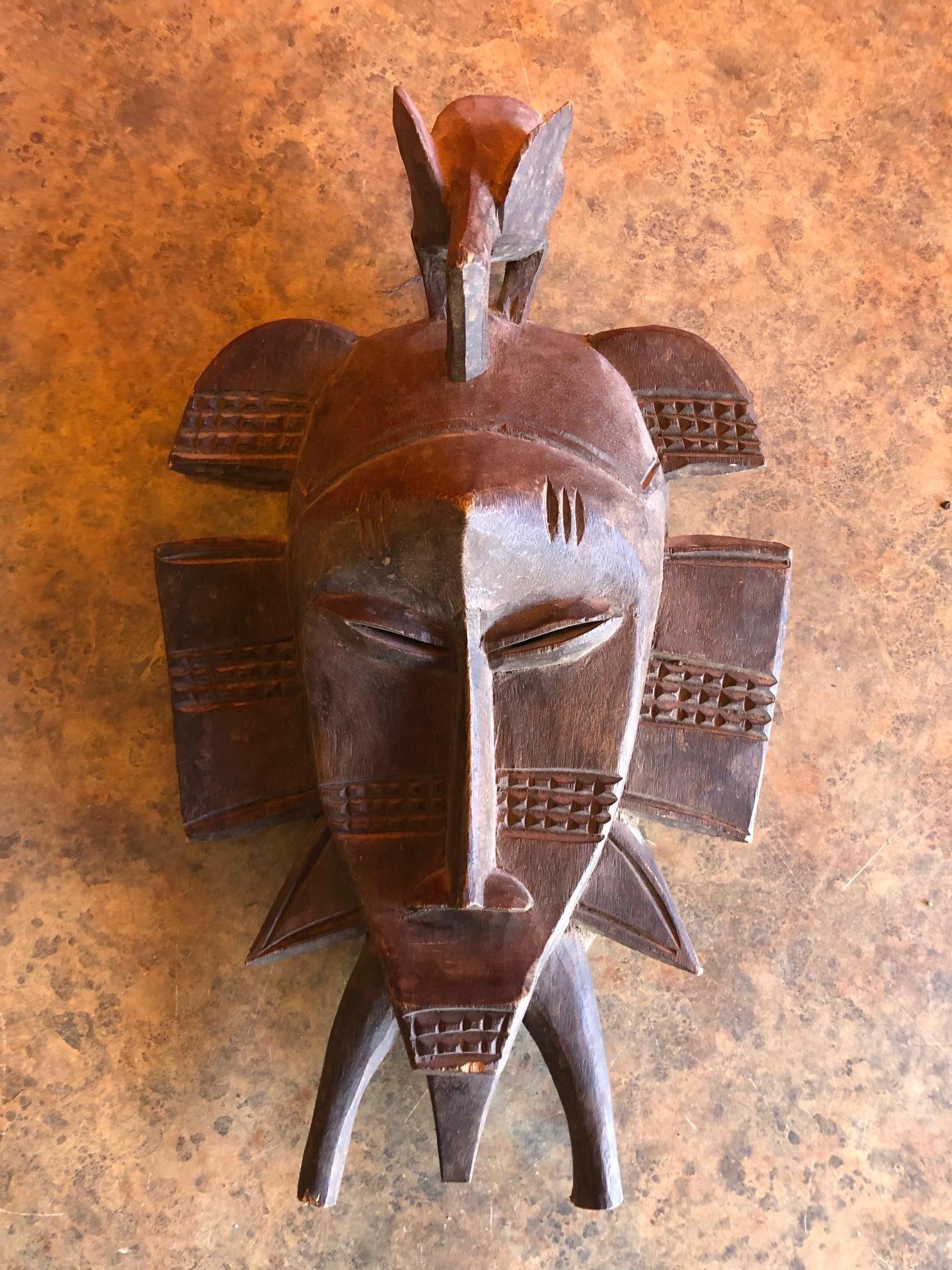 Hand carved Primitive Senufo Kepelie tribal mask with head bird from the Ivory Coast (Cote d'Ivoire), Africa, circa 1950s. The Kpelie is an intricately carved mask hosting human and animal features which is used in initiation ceremonies. This