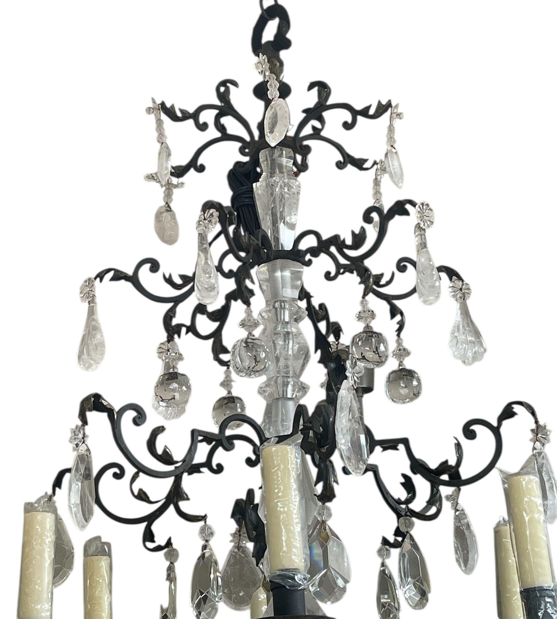 A magnificent and highly detailed twelve-light chandelier composed of hand-carved and polished rock crystal and hand-forged wrought iron. The spectacular rock crystal center shaft anchors five gracefully tiered arms of finely wrought iron, each