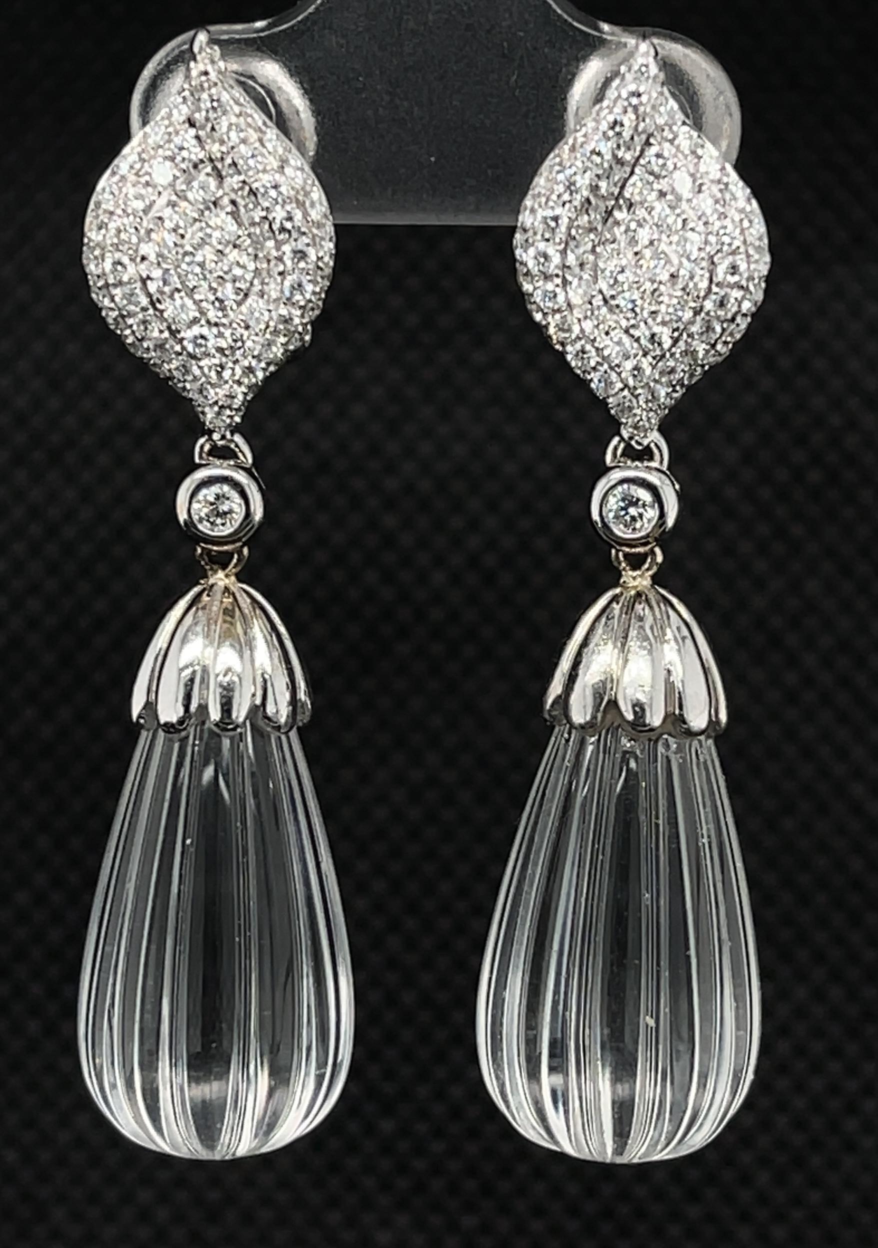 These unusual dangle earrings feature hand-carved rock crystal briolettes dangling from gorgeous 18k white gold diamond pave tops. Over a carat of brilliant white diamonds sparkle in these gorgeous earrings fashioned with French clip backings for