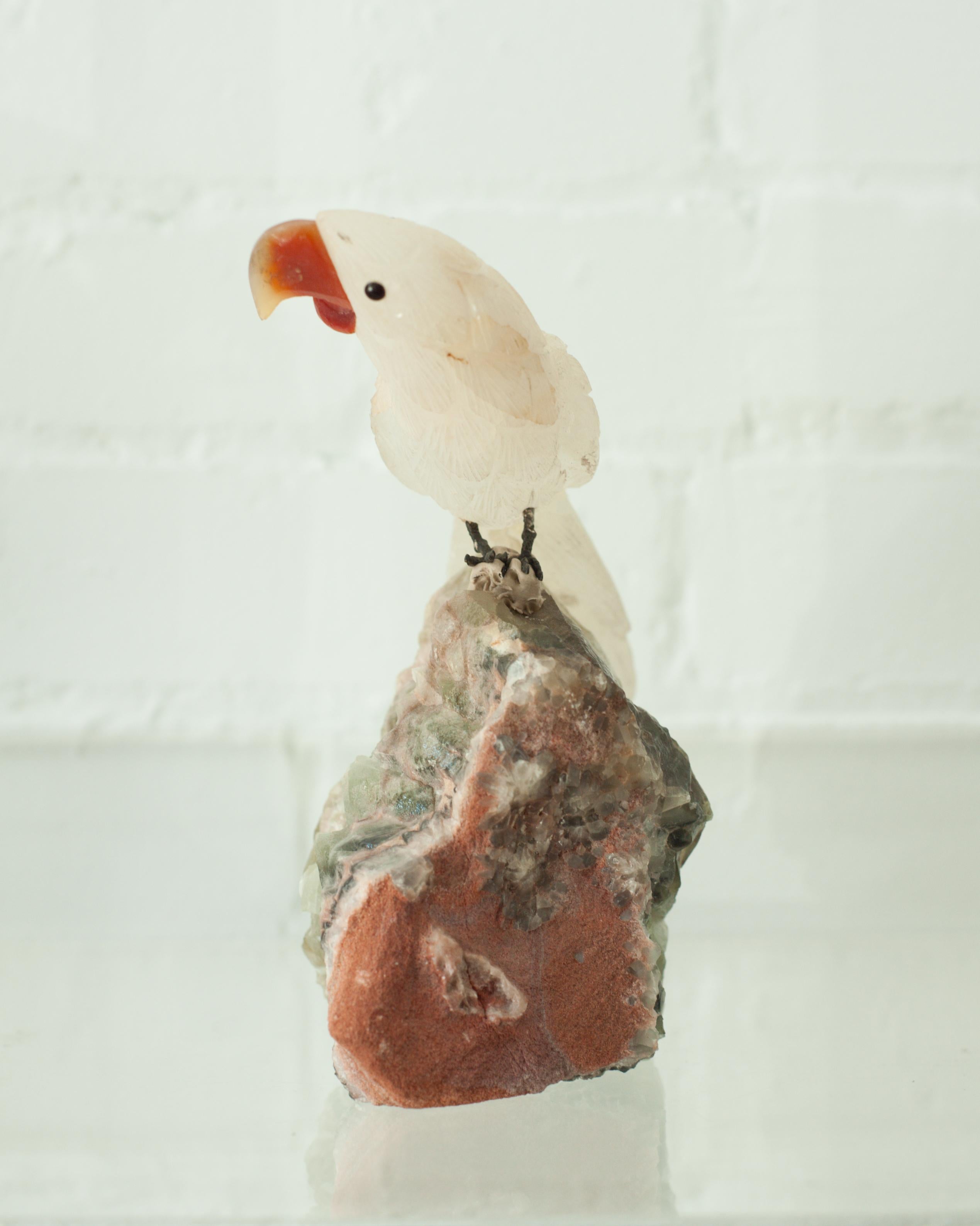 A beautiful hand carved rock crystal parrot mounted on a rough green amethyst base. This exotic bird is a decorative combination of ornithology and geology.