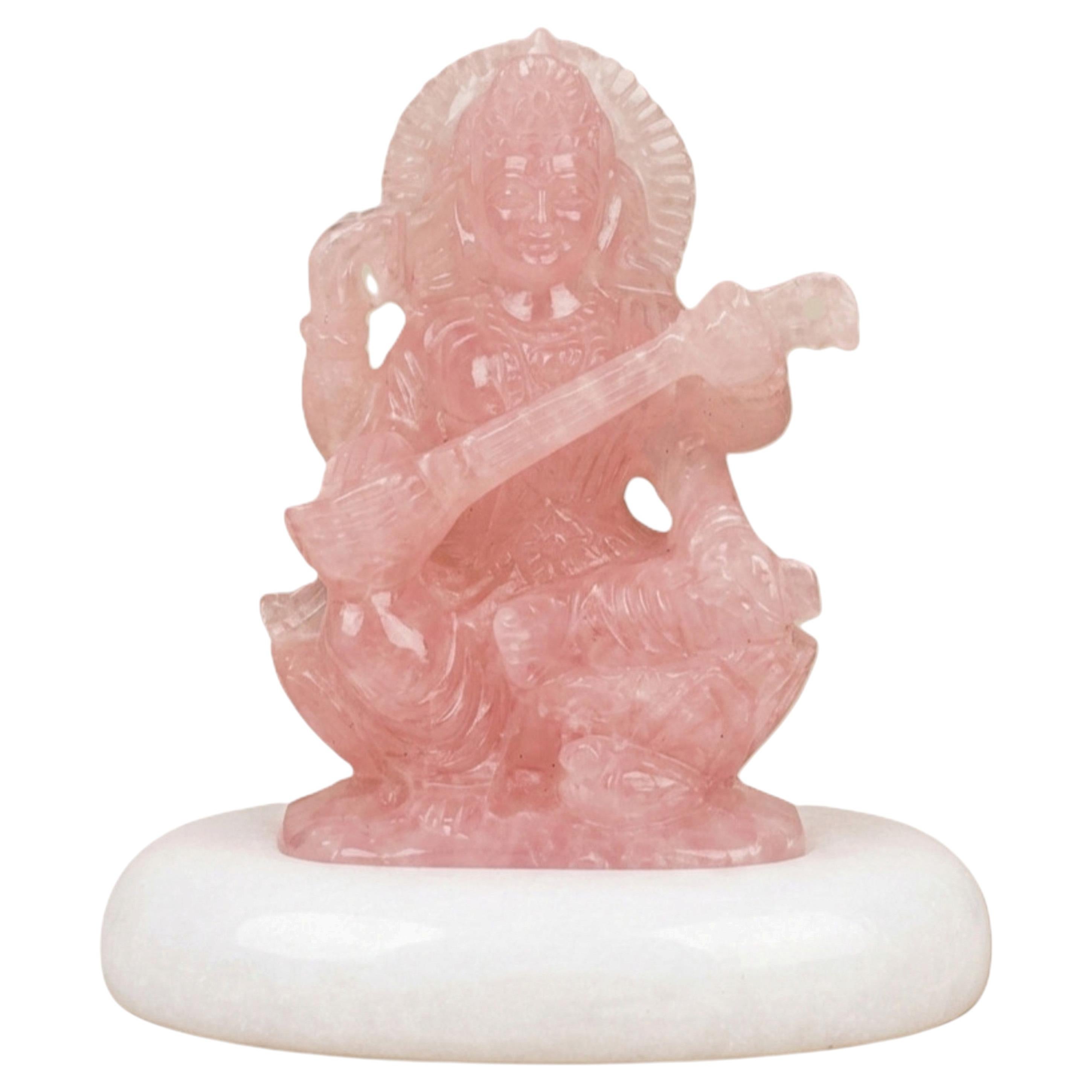 Escultura de la diosa Saraswati, tallada a mano en cuarzo rosa, sobre una base de mármol blanco