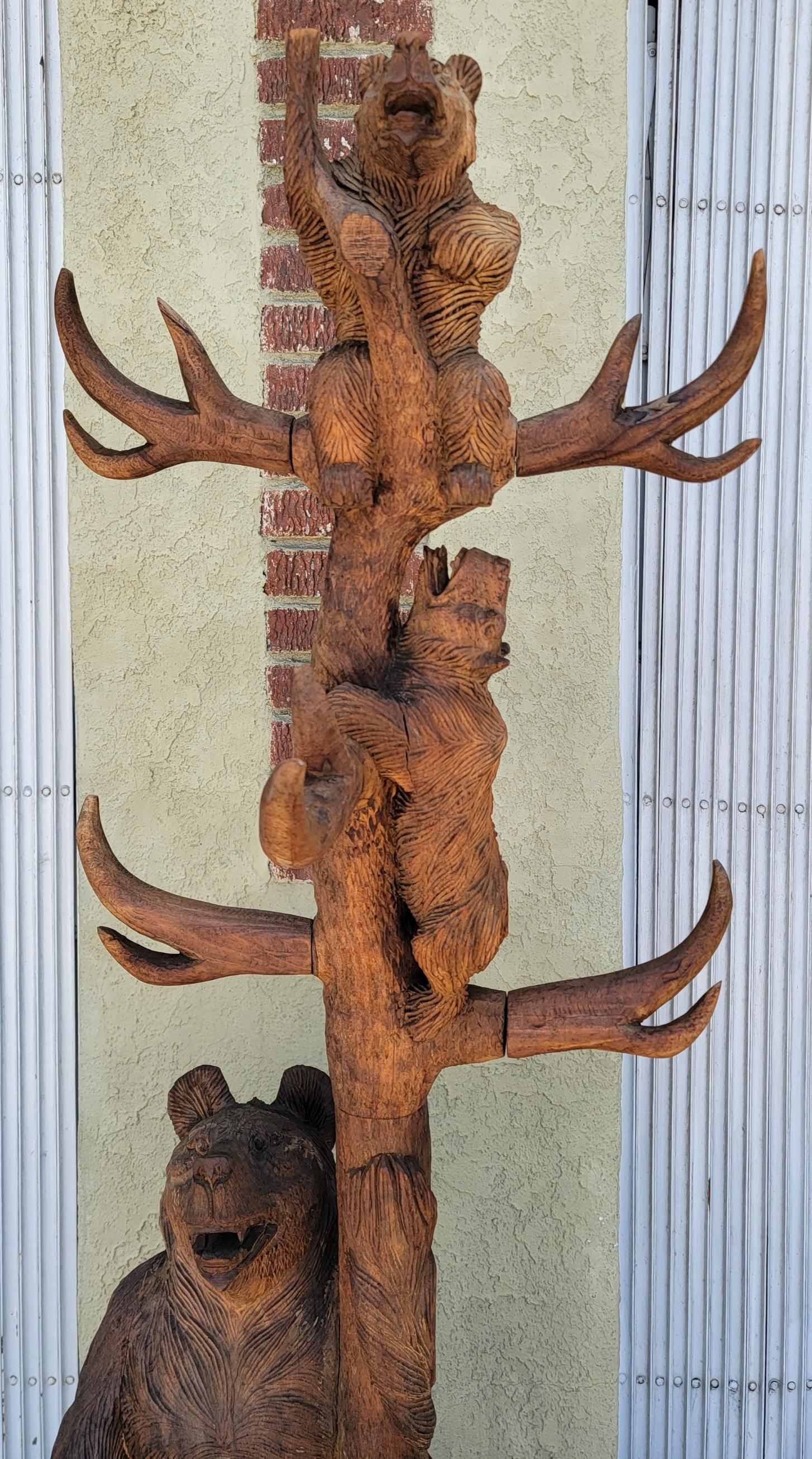 This rustic hand carved hat and coat tree with carved momma bear and baby cubs climbing up the tree. The condition is very good with wear and tear consistent from age and use. The base is on four hand carved feet and has a place for the umbrellas at