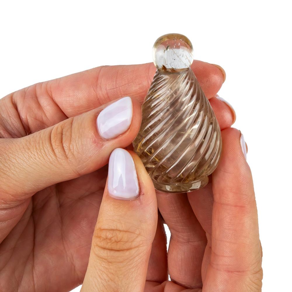 Le corps en forme de goutte d'eau en quartz rutilé fumé est entièrement sculpté à la main de manière classique avec un motif en spirale. Il est doté d'une couverture en quartz rutilé qui se glisse dans la pochette. 

Créé par Abdul Zuber, Jaipur