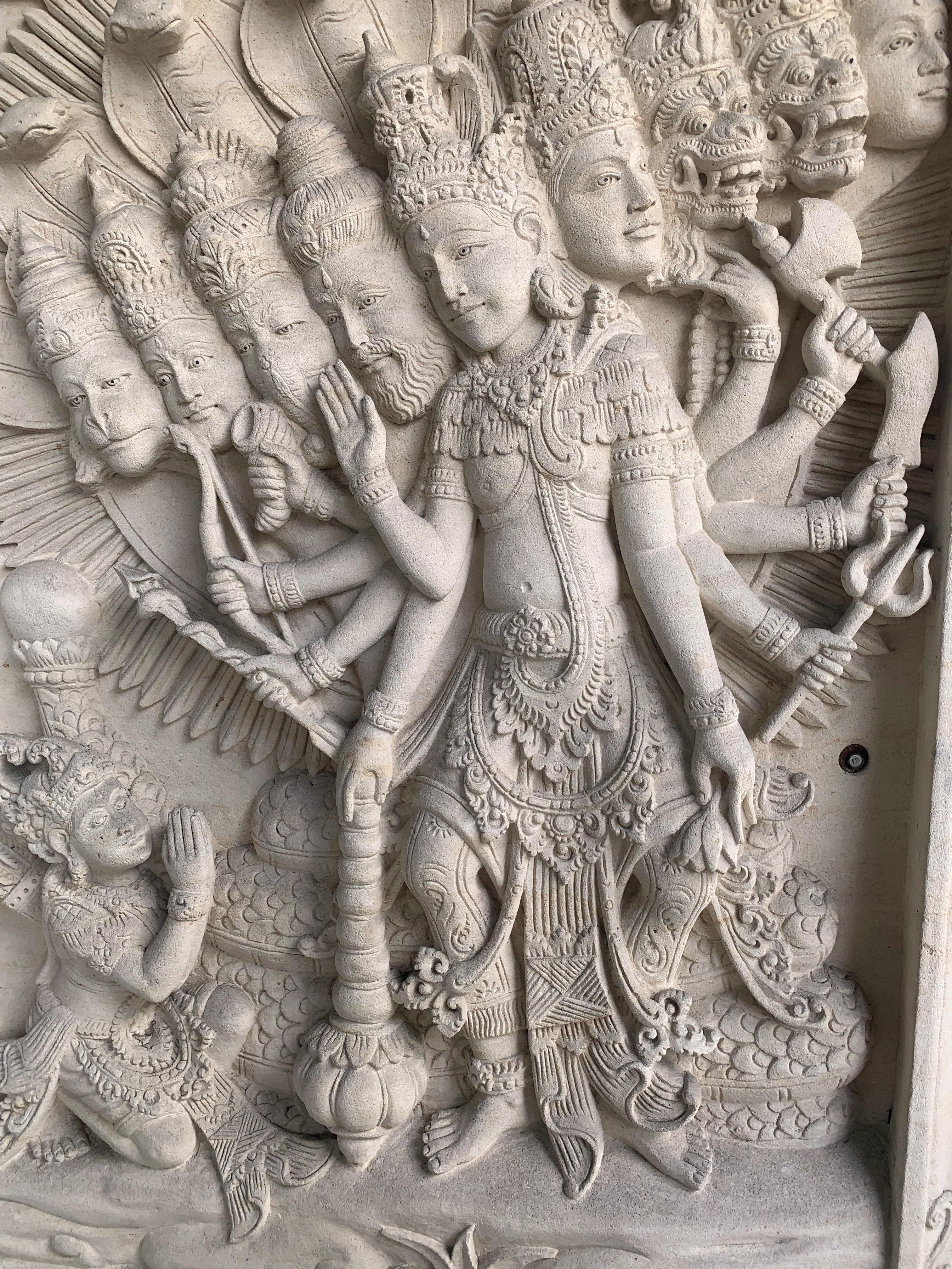 A hand-carved sandstone panel from Bali, Indonesia. This panel was meticulously carved and features 10 Hindu Gods that are draped by 6 cobras in the background. Some of the gods depicted in this carving include Hanuman on the far left, Ganesha;