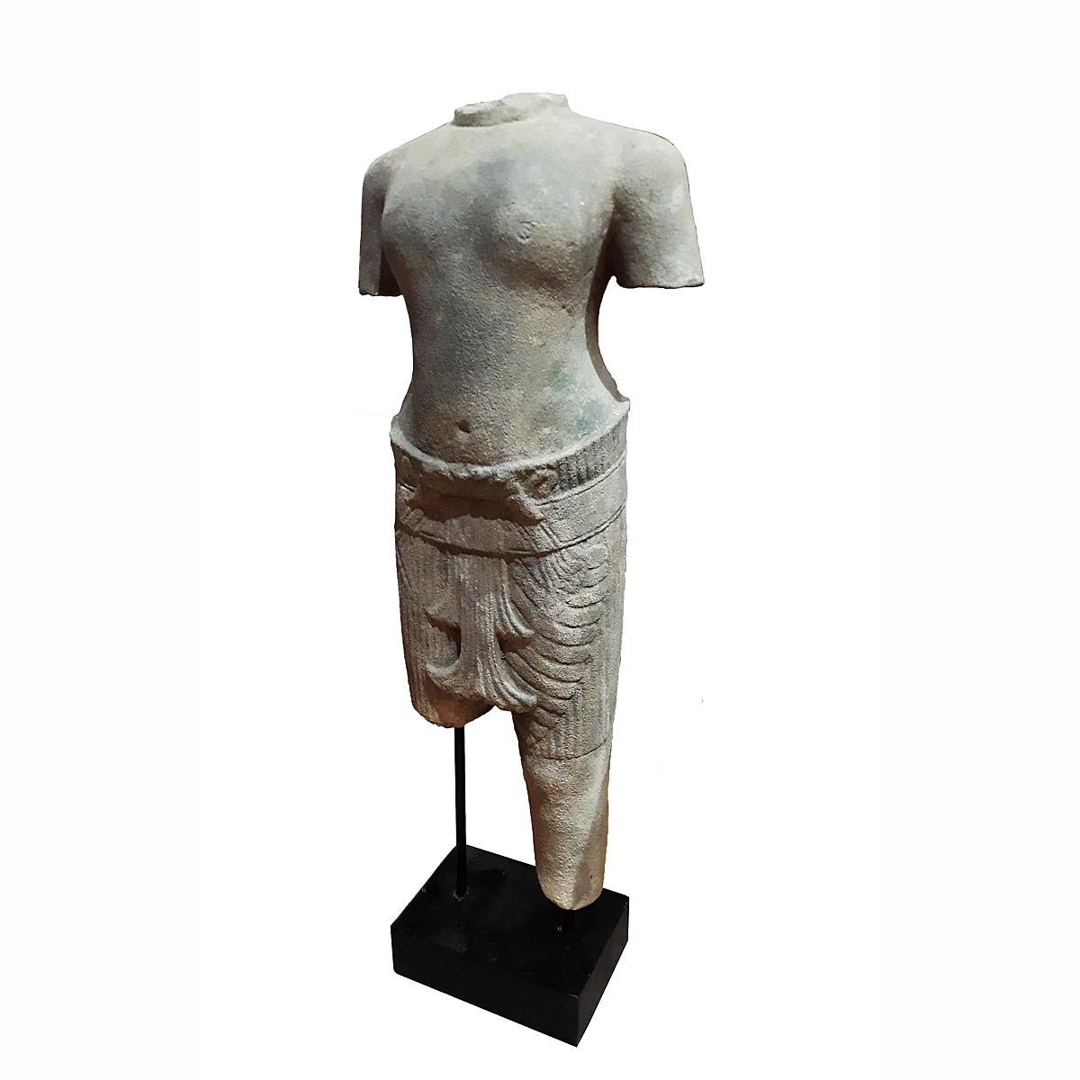 A sculpture of a male torso in traditional attire, hand carved from a single piece of sandstone. From Thailand. Mounted on a wood / metal stand. At 28 inches high, this torso makes an eye-catching accent for a table, console or desk.