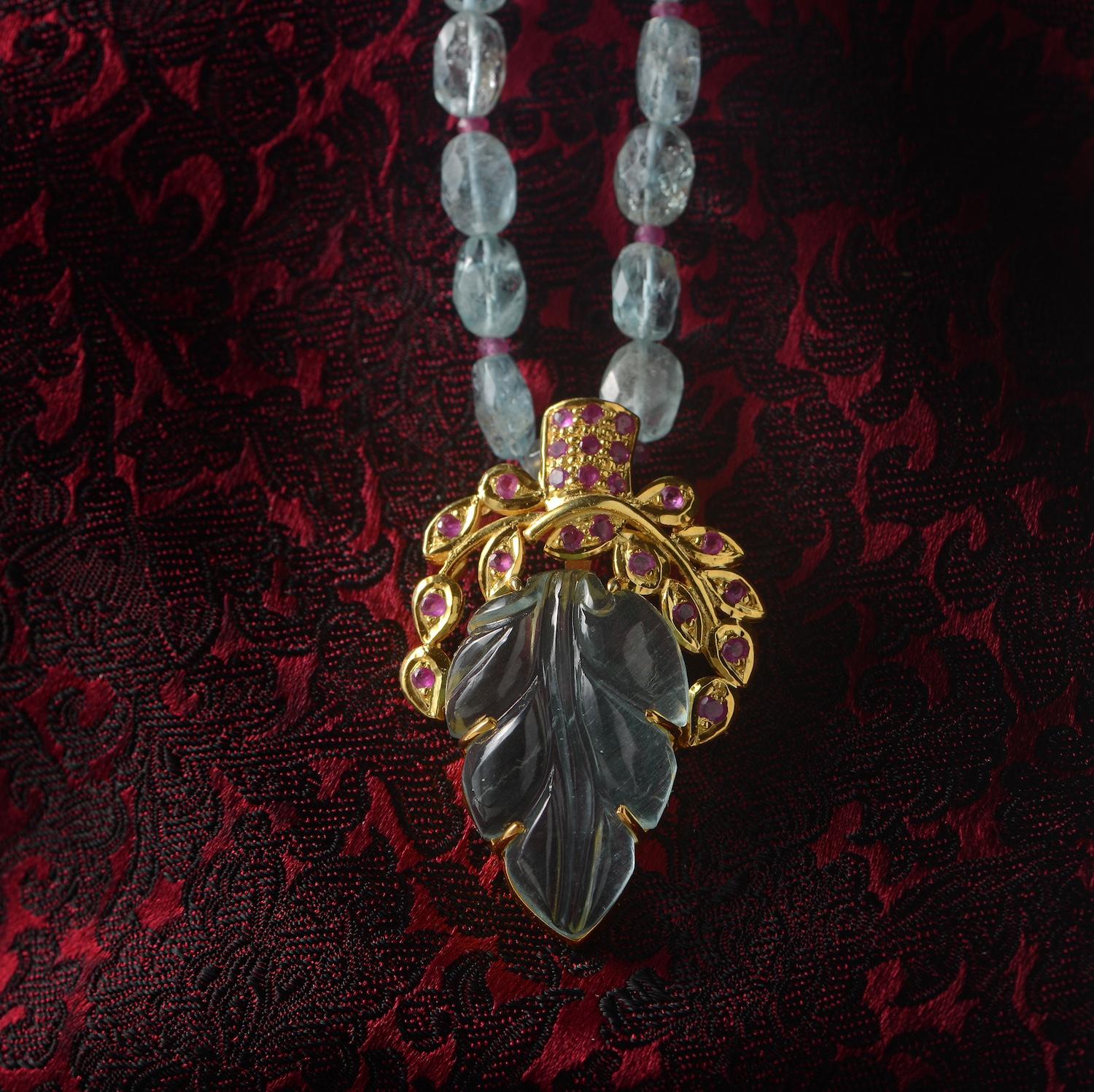 Using the ancient art of stone-carving, this one-of-a-kind aquamarine pendant has been hand-carved and hand-engraved in our workshops. Made in sterling silver coated with 24ct gold vermeil, it is embedded with rubies. It comes with a 28 inch