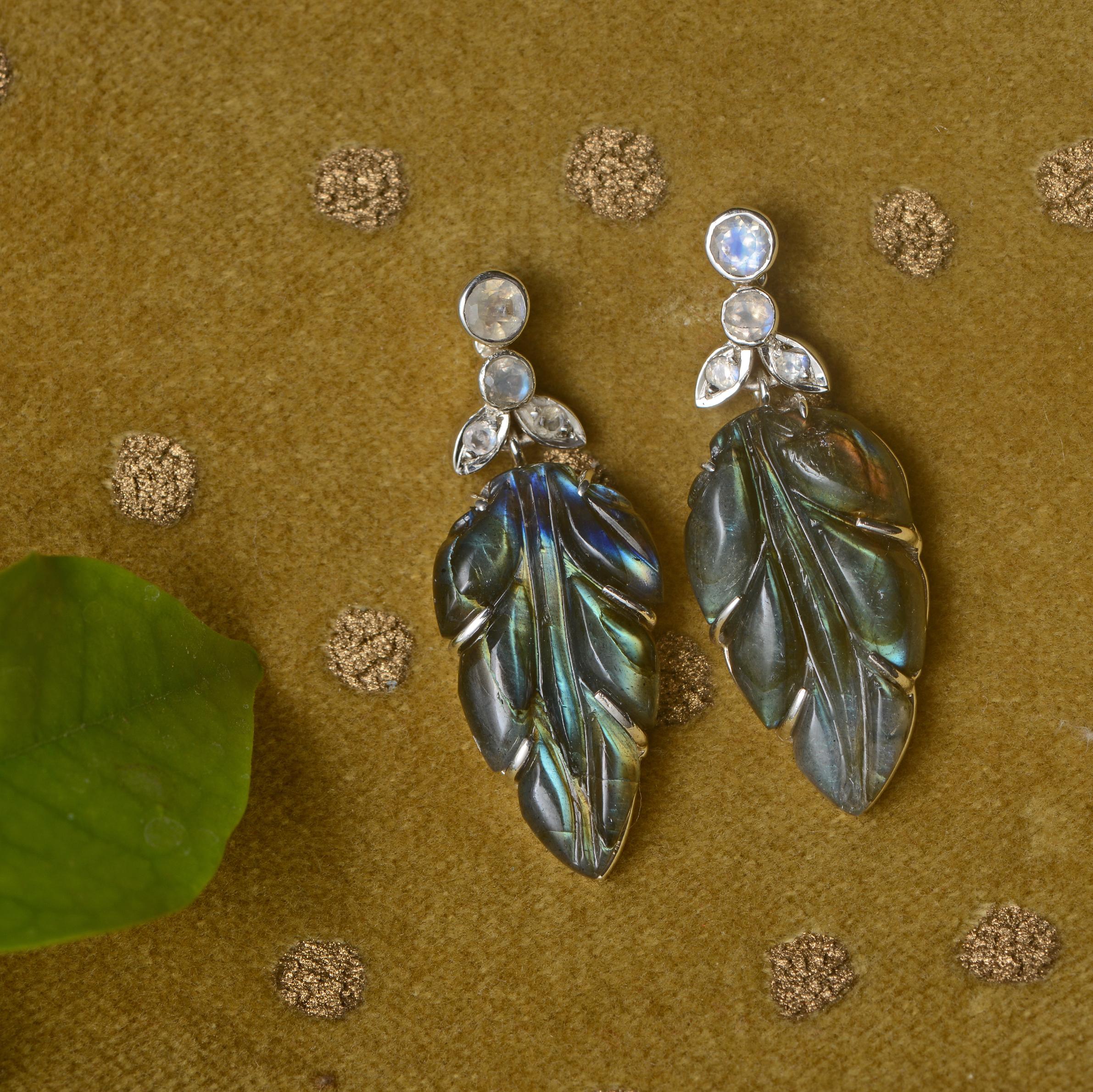 Using the ancient art of stone-carving, these stunning one-of-a-kind labradorite earrings have been hand-engraved and hand-carved into leaf patterns. The earrings which are made in sterling silver are embedded with rainbow moonstones at the top, and