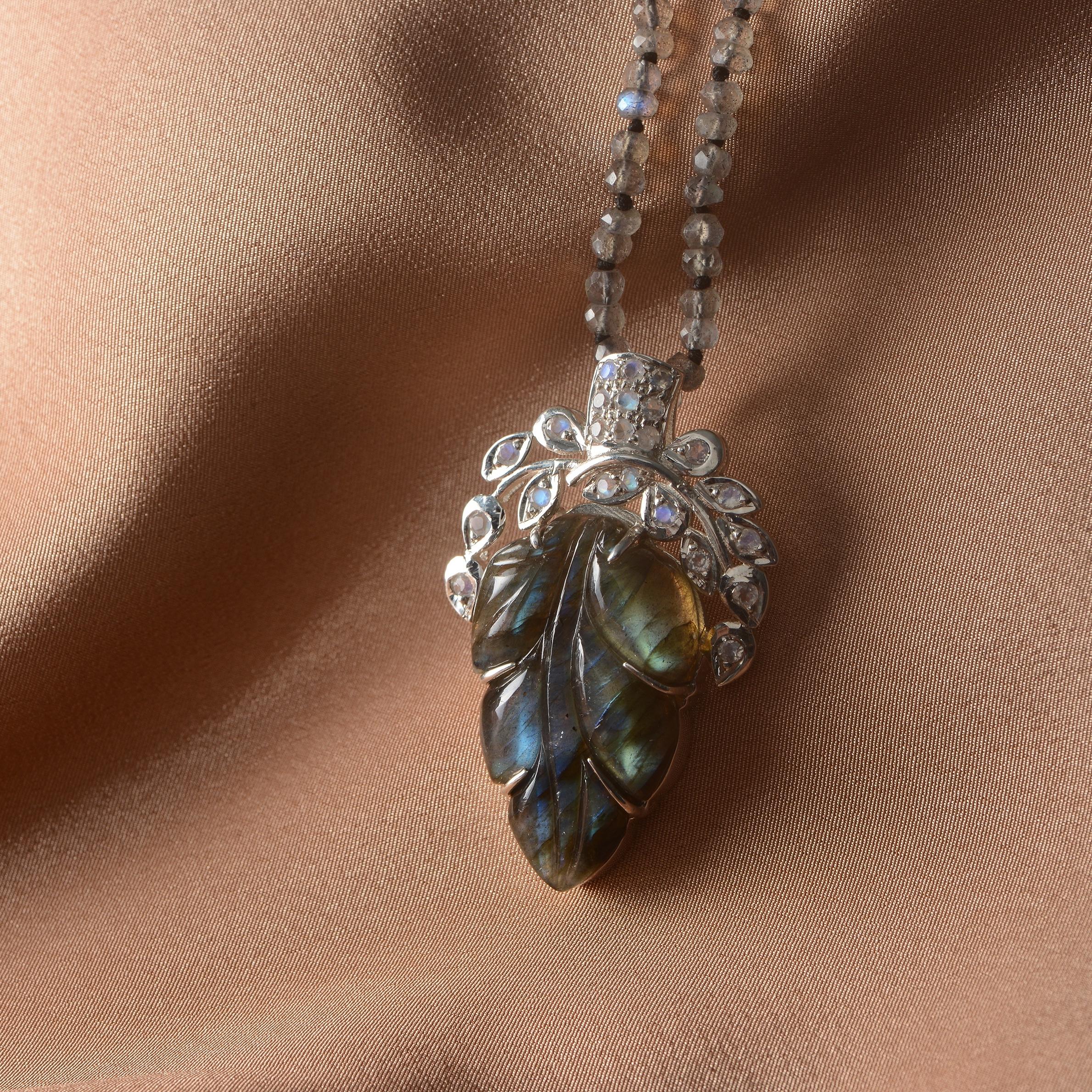 Using the ancient art of stone-carving this one-of-a-kind labradorite pendant has been hand-engraved and hand-carved using a leaf pattern. The pendant which is made in sterling silver has rainbow moonstones embedded in the top and comes with a 28
