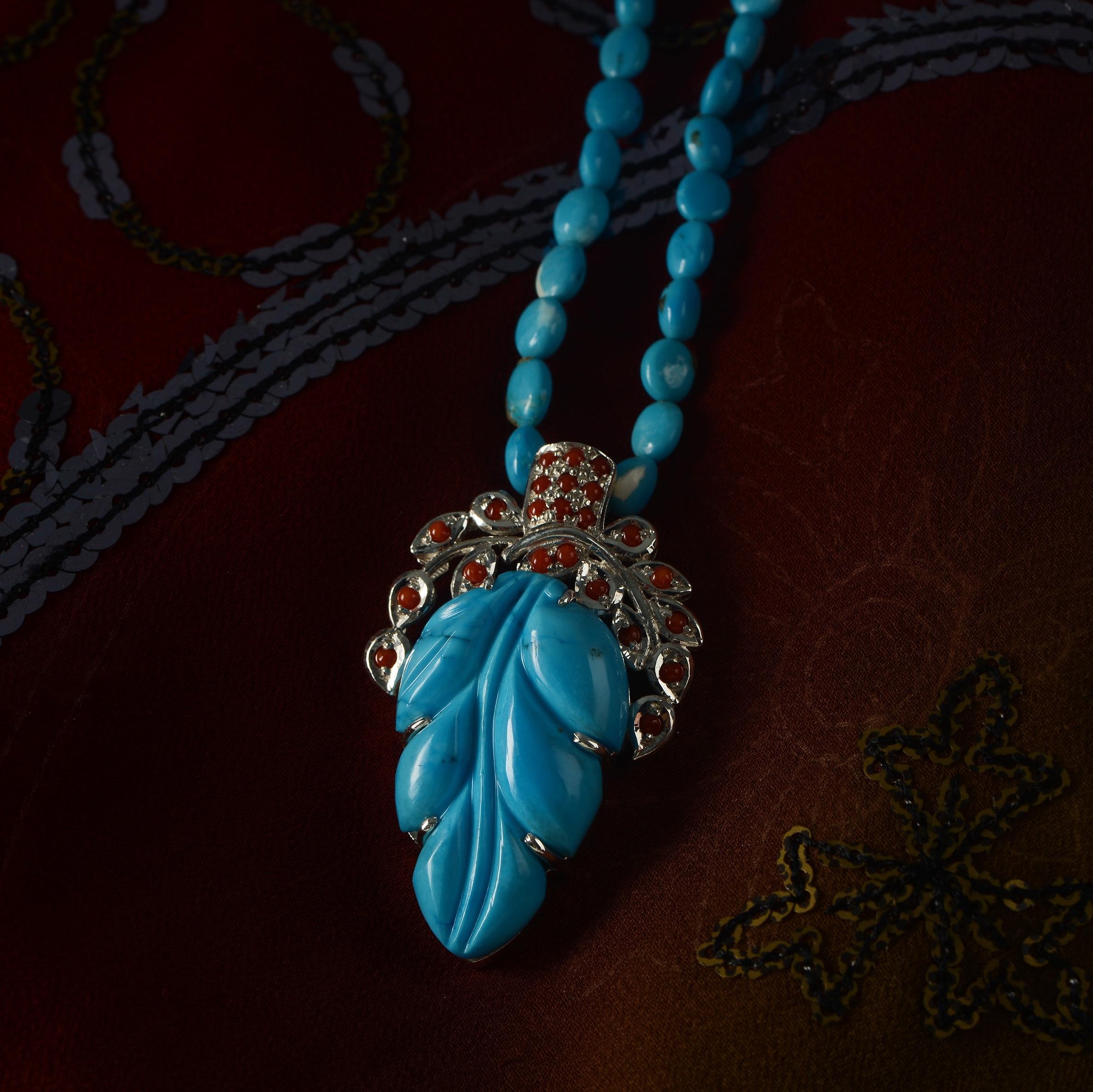 Using the ancient art of stone-carving, this stunning one-of-a-kind turquoise pendant has been hand-carved into the shape of a leaf and then hand-engraved. The top of the pendant which is made in sterling silver, has been embedded with red corals.