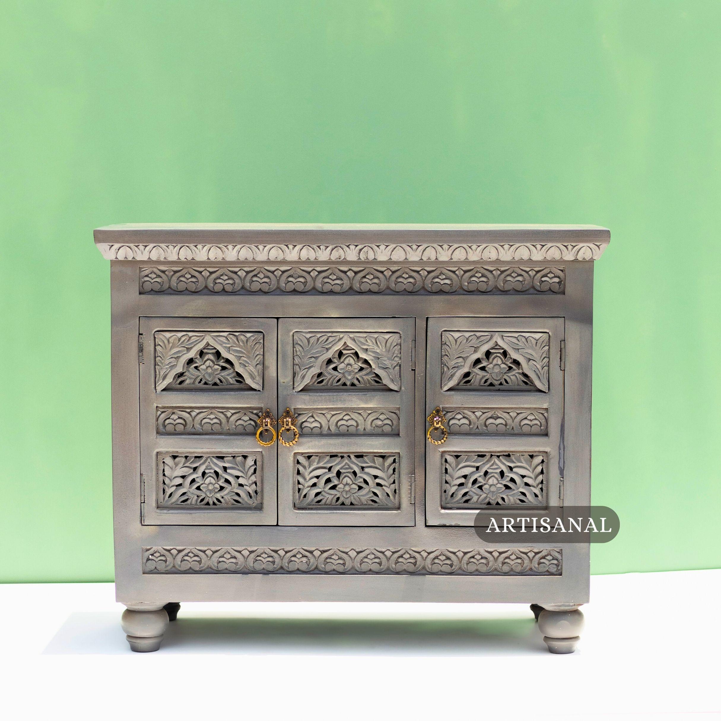 This exquisite cabinet is a testament to traditional craftsmanship, entirely hand-carved from solid wood with remarkable attention to detail. The piece features intricately carved floral and leaf motifs across its panelled doors and borders,