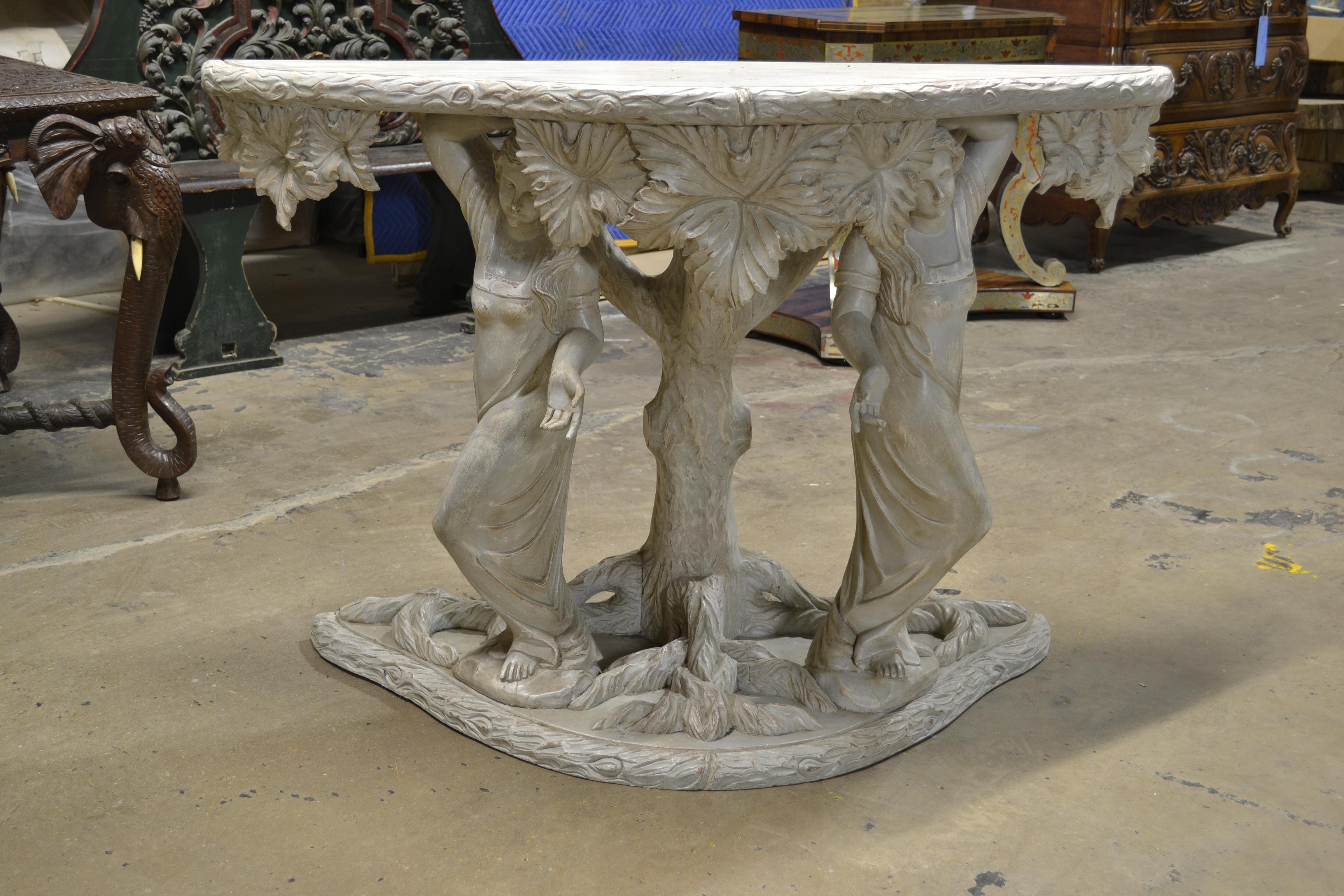 We call this our Romantic console because its charms are unmistakable. The early 20th century piece features two nicely carved maidens perched on a shaped base. Arising between them is a carved tree supporting leaves and a shaped top. The piece has