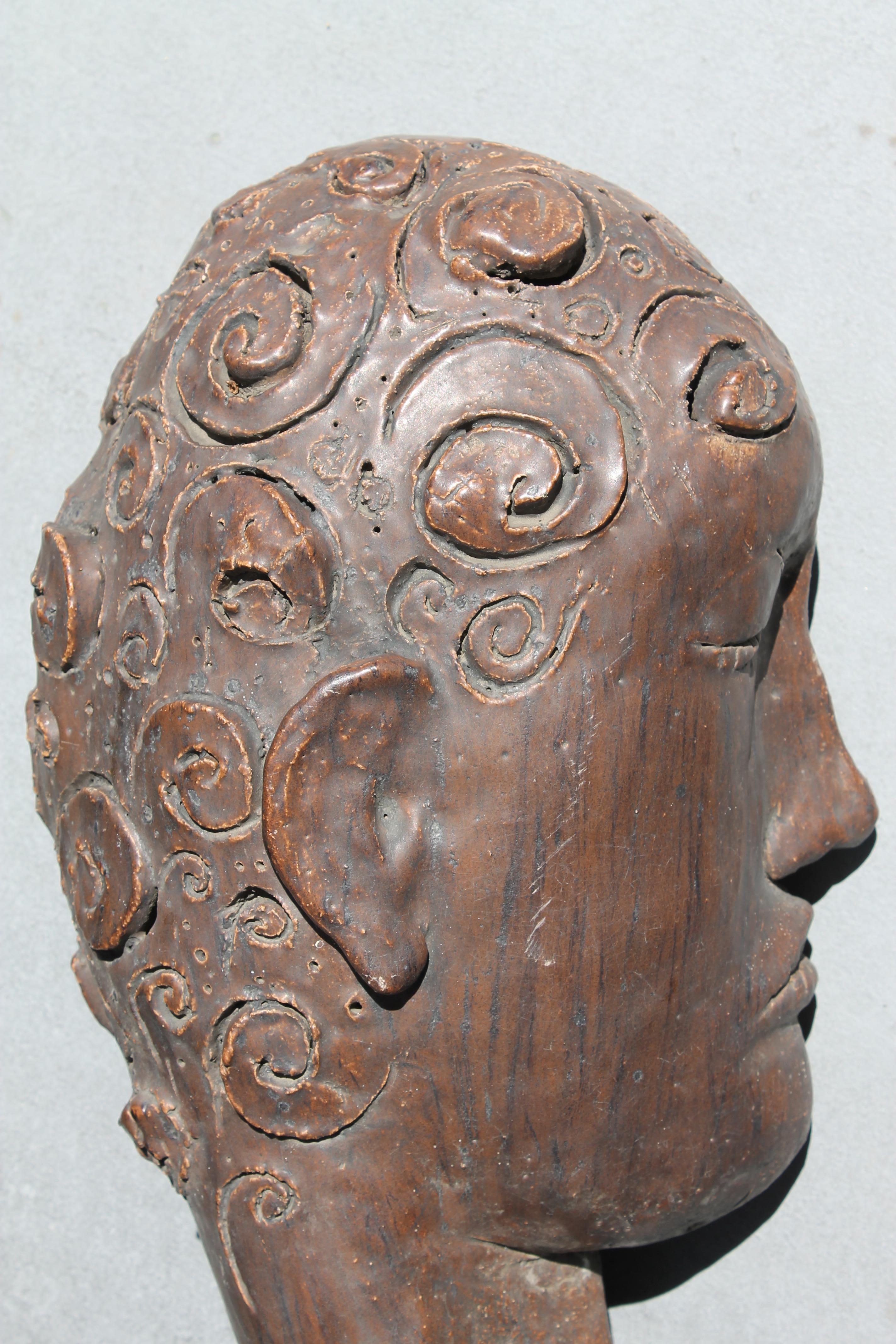 Beautiful hand carved stoneware face sculpture by James Kouretas (1947-2016).  Sculpture has 2 holes in the back most likely for hanging on the wall or could be displayed on a table.  Signed on the bottom portion of neck.  Sculpture measures 17.5