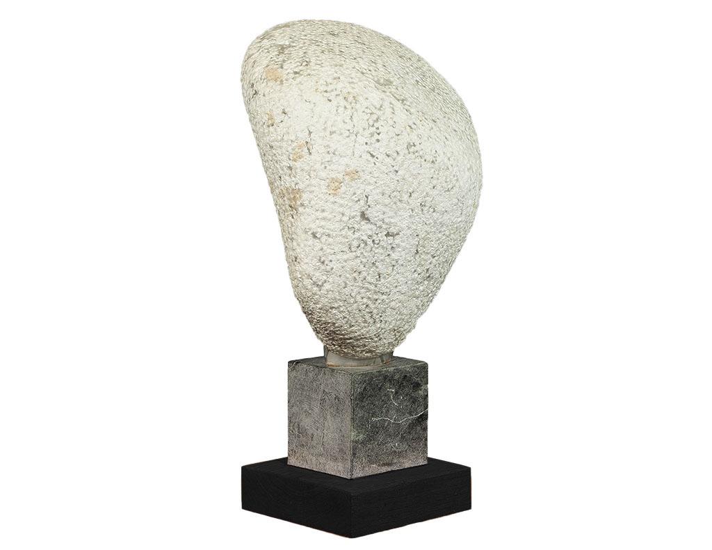 Combination of naturally formed and carved stone sculpture of an abstract head. Mounted on a two-tiered soapstone and black oak base. Made by Canadian artist Daniel Pokorn, Signed and dated 1979.