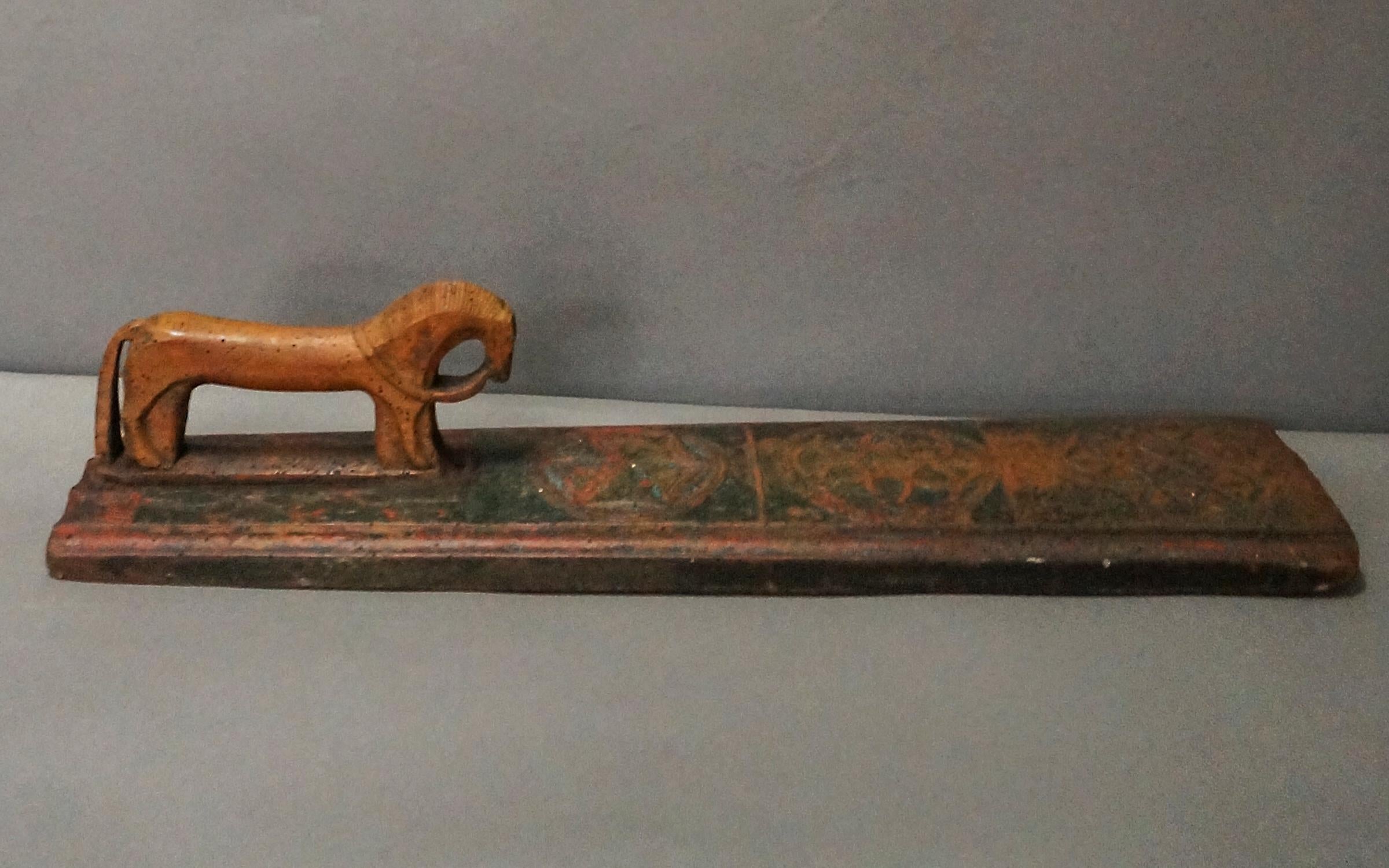 Mangle board in original green and salmon paint, Sweden dated 1818. The horse-shaped handle has an incised main and articulated reins and tail. On either side of the horse are twining vines in baskets. On the board itself are three compass-drawn