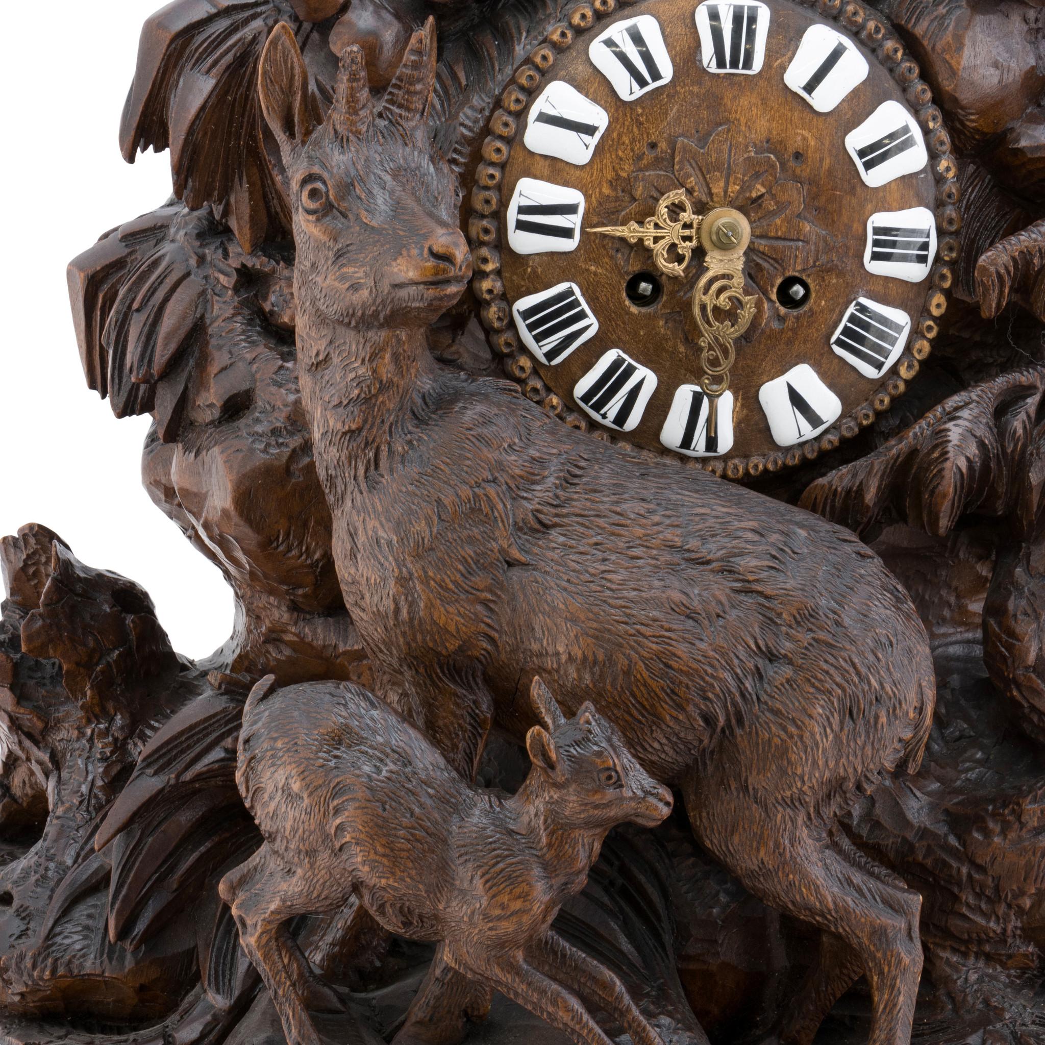 Massive Black Forest heavily carved mantle clock with eagle finial having chamois, doe and fawn below on rocky ledge. Heavily carved with foliage design. Clock face having white roman numerals with brass hands. Fully restored and in working
