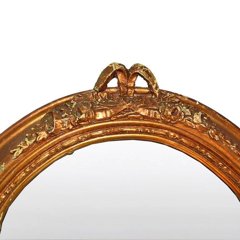 Long tall giltwood mirror with gold hand-carved rosette and floral moulding around the edges. The top of the piece features a bowl and bottom edges are rounded. Would make a wonderful addition to any space, or a great piece for creating a gallery