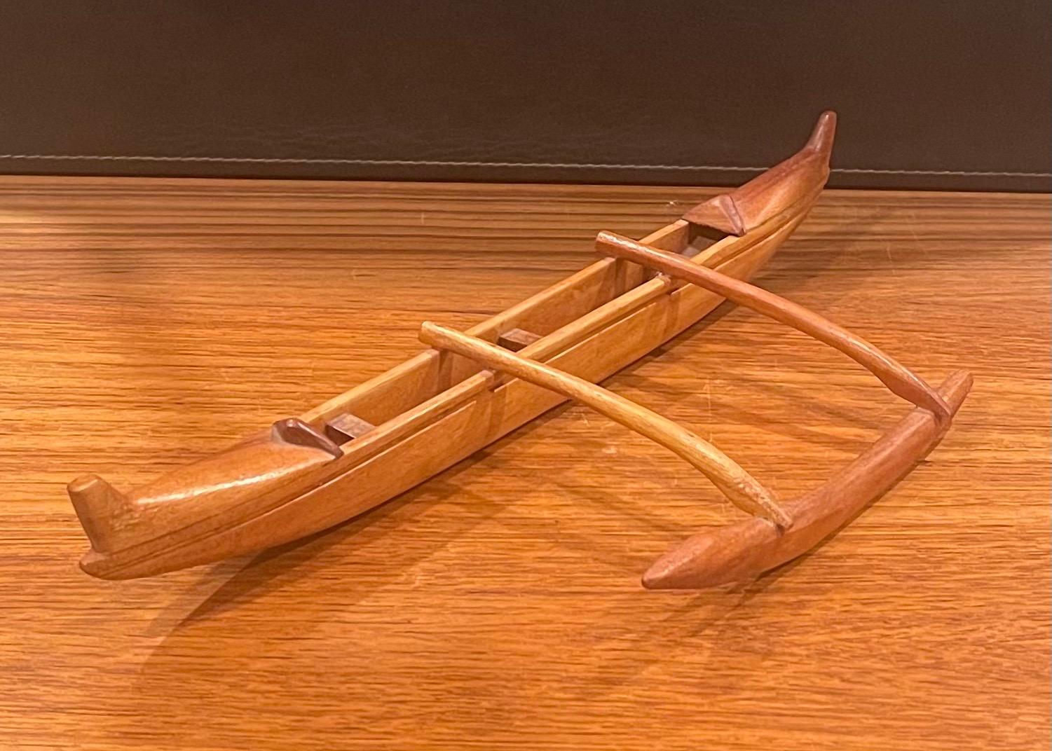 A very cool hand carved teak outrigger canoe sculpture, circa 2000s. The piece is in excellent condition and measures 16