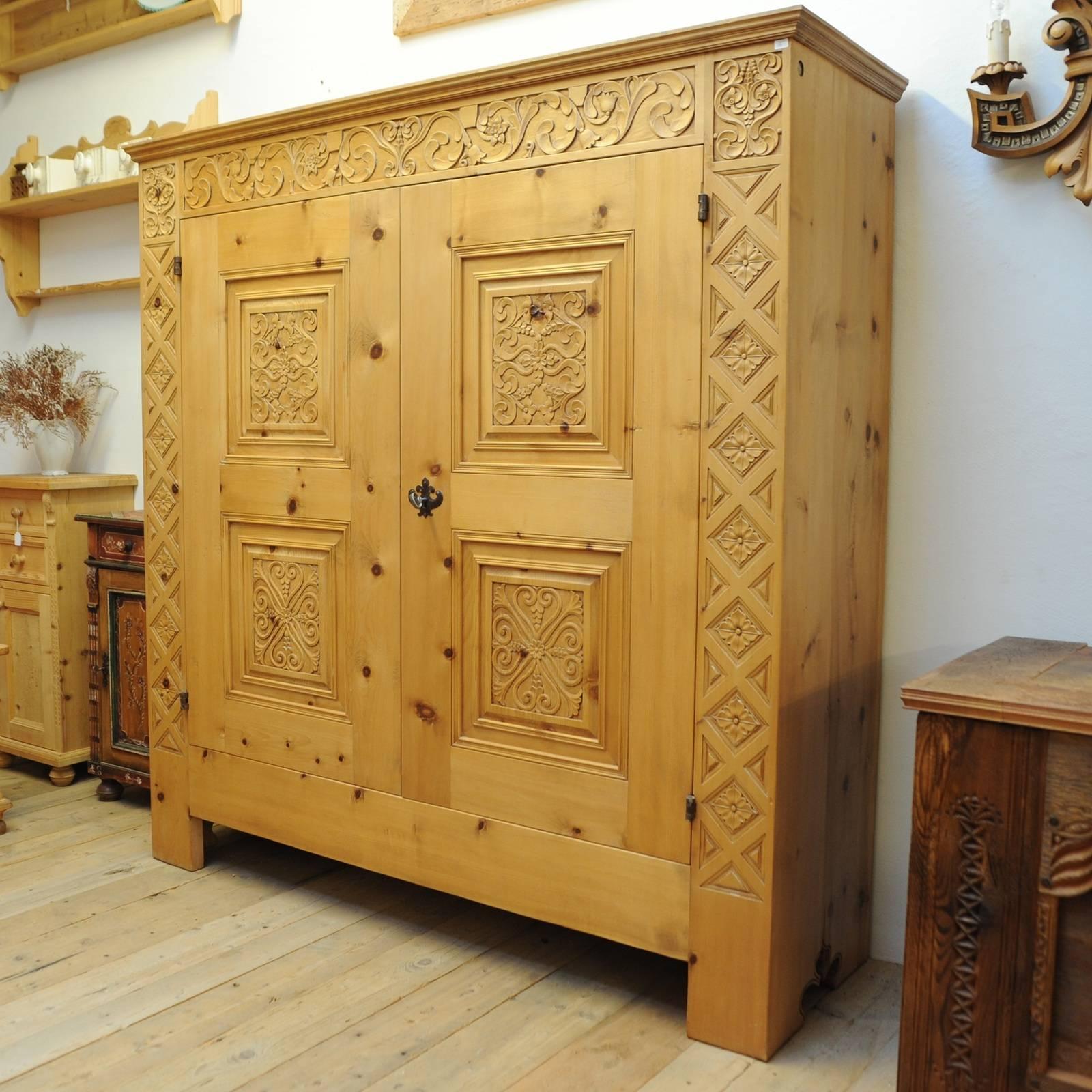 This elegant cabinet was crafted of Swiss pine wood in a Minimalist shape that was planed by hand in a stunning pattern that combines geometric and symmetrical decorations with sinuous and floral motifs. The two doors boast hinges and handles hand