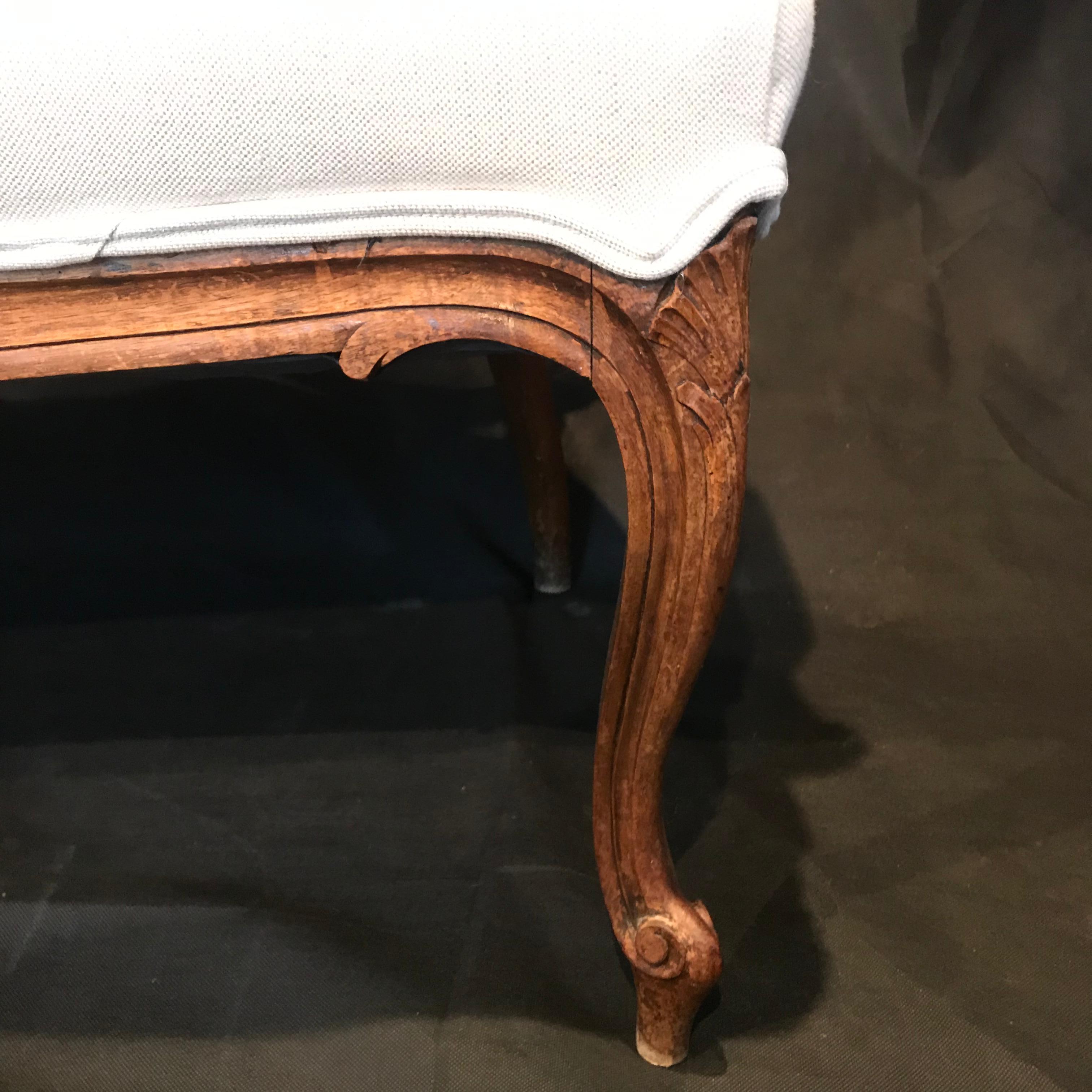 A lovely antique Louis XV style carved walnut sofa having a carved walnut frame finished in its original rich walnut color stain. Frame is ornately adorned with crests and scrolls.  #3052
Brand new neutral French linen cotton fabric with double