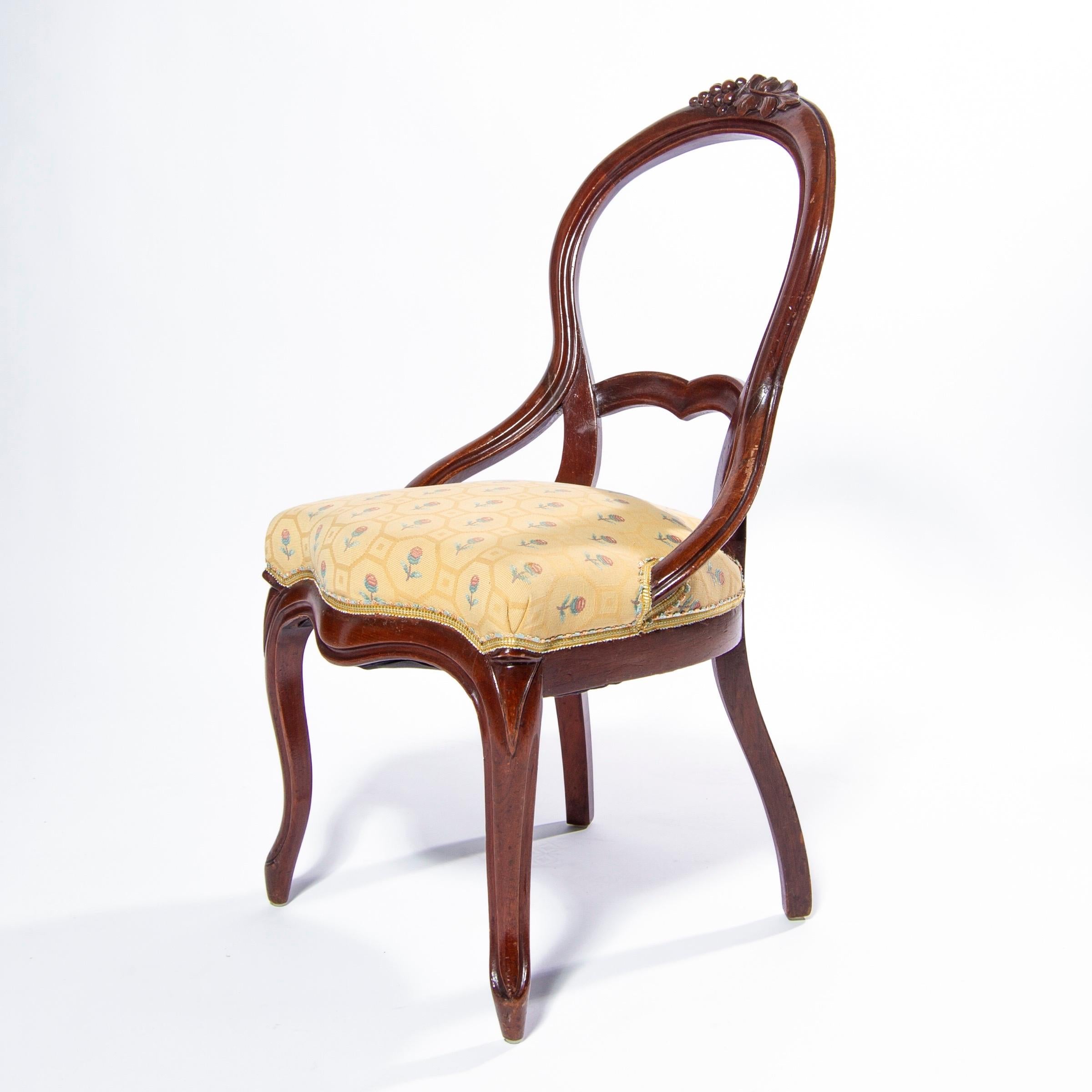 Exceptional Queen Anne chair rendered in walnut with a hand carved grape motif and woven fabric with ribbon trim, England.