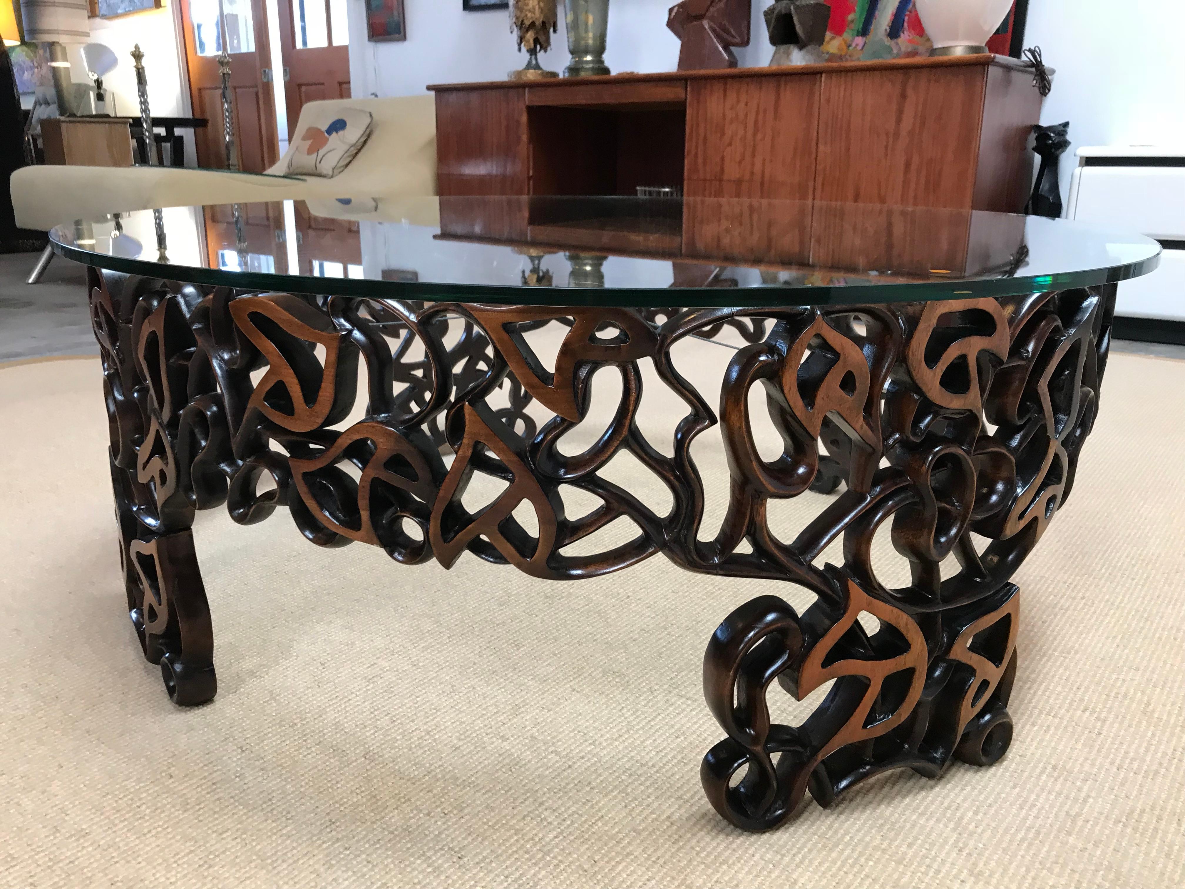 Unique hand-carved walnut coffee table by artist Doug Edge. The intricate design resembles delicate lace. Four legs and glass top.
A steel cable stabilizes it. This work took a year to be achieved! It is a perfect example of workmanship.
Doug Edge