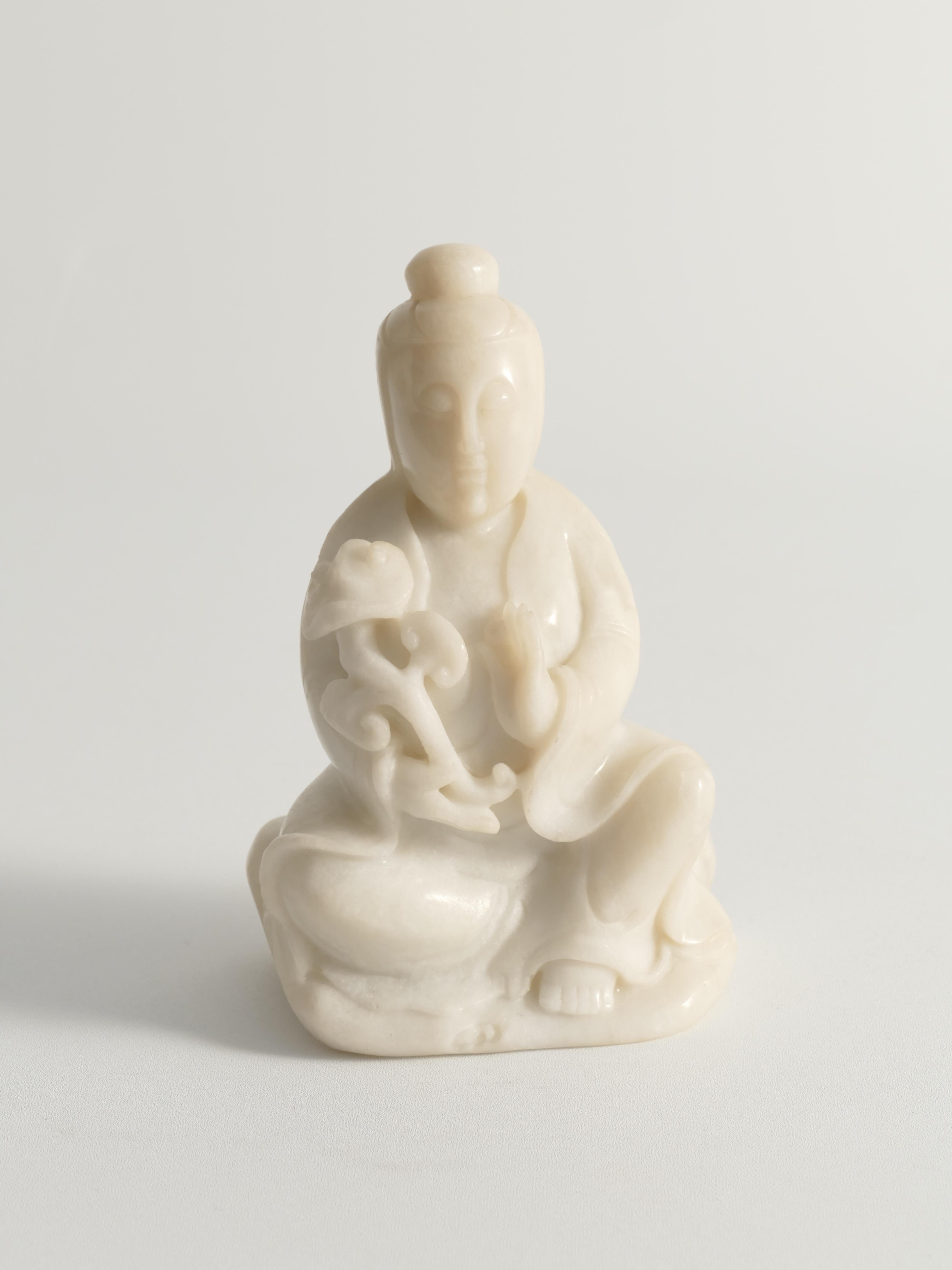 Diese exquisite Guanyin-Figur aus dem frühen 20. Jahrhundert ist meisterhaft aus einem einzigen Stück reinen, zarten weißen Alabasters geschnitzt. Der Alabaster, der für seine feste und doch warme Beschaffenheit bekannt ist, verleiht der Figur eine